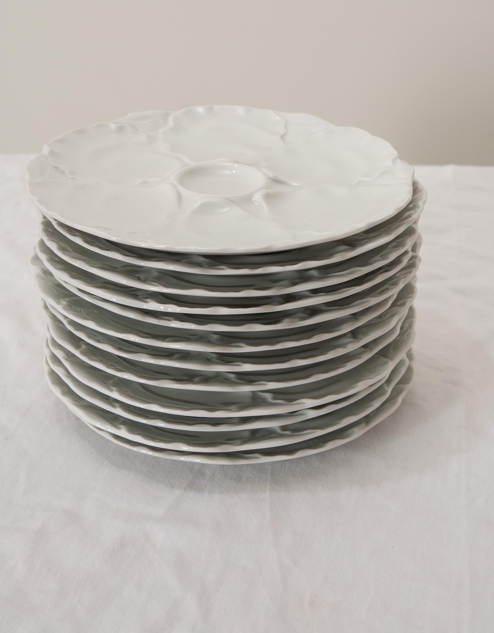 An elegant set of twelve French white oyster plates made by Hutschenreuther Porcelain in Germany during the 20th Century. These plates are fabulous with glossy molded and shaped centers and fluted edges. The maker's stamp can be found on the reverse