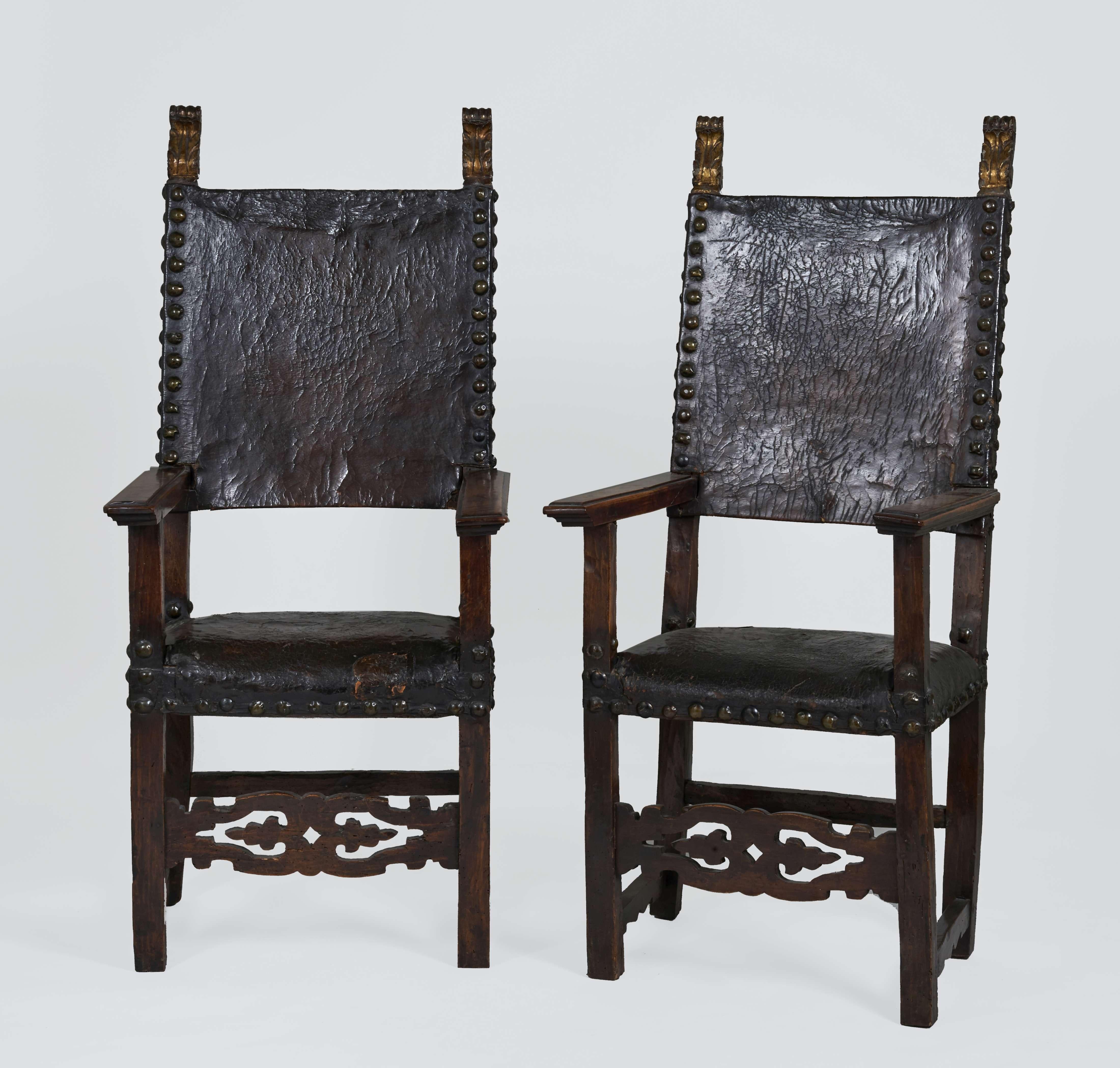 Pair of walnut chairs with openwork crossbars, leather upholstery and brass nails. The wood frame is partly gilt with a palm leaves and scrolls decor.