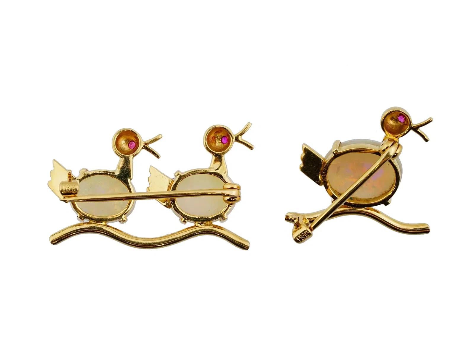 Lote de dos broches de joyería de oro de 18 quilates adornados con ópalos. Diseñado como pájaros sentados en una rama. Los cuerpos de las aves están hechos de ópalos. En los ojos de los pájaros hay engarzadas pequeñas piedras de rubí. Cada pieza
