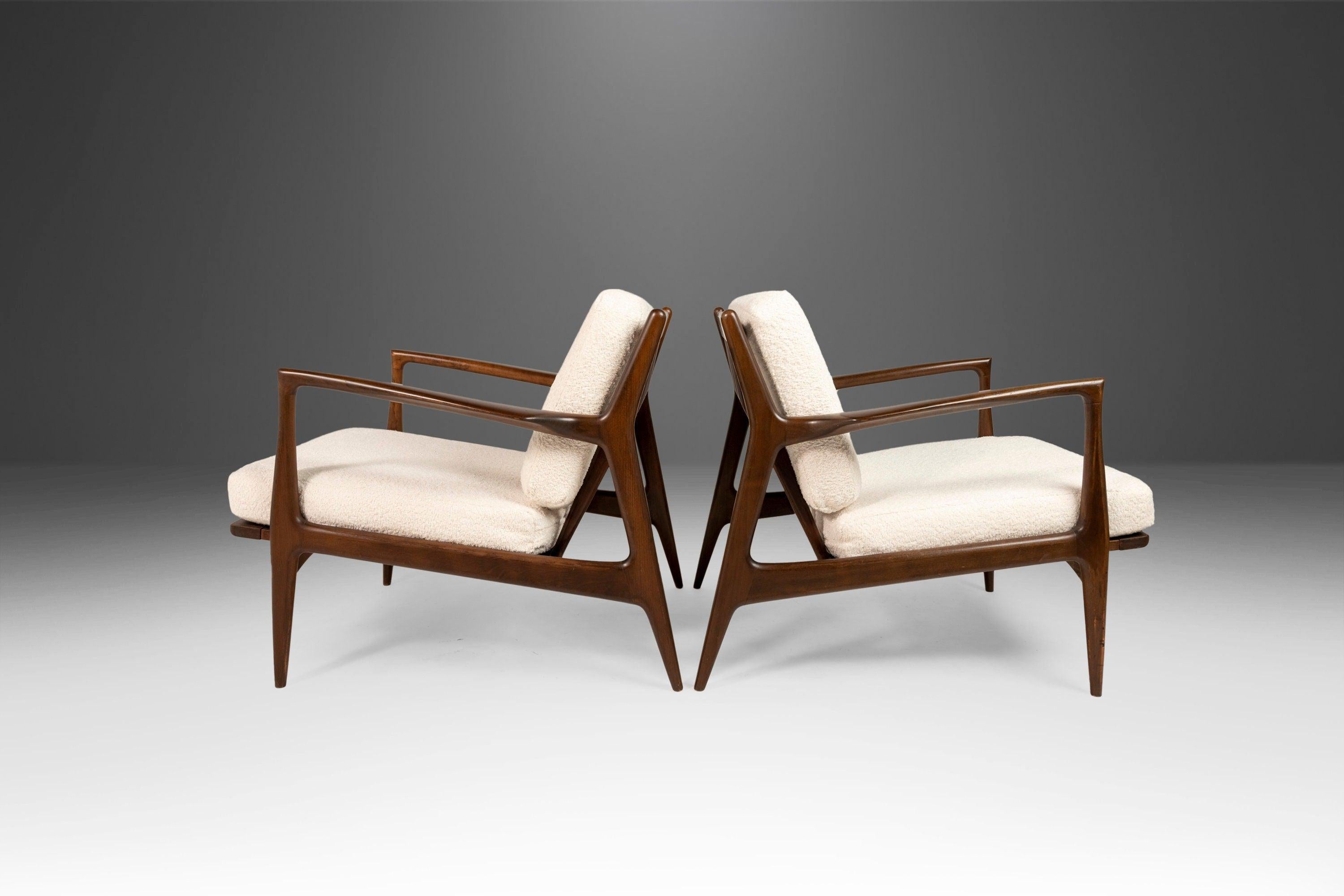 A sensational set of two lounge chairs designed by Ib Kofod-Larsen for Selig in Denmark. This outstanding 'Blade' chair has an original Selig manufacturer's badge and was built to high Danish standards in the 1960's using walnut wood. The seat and