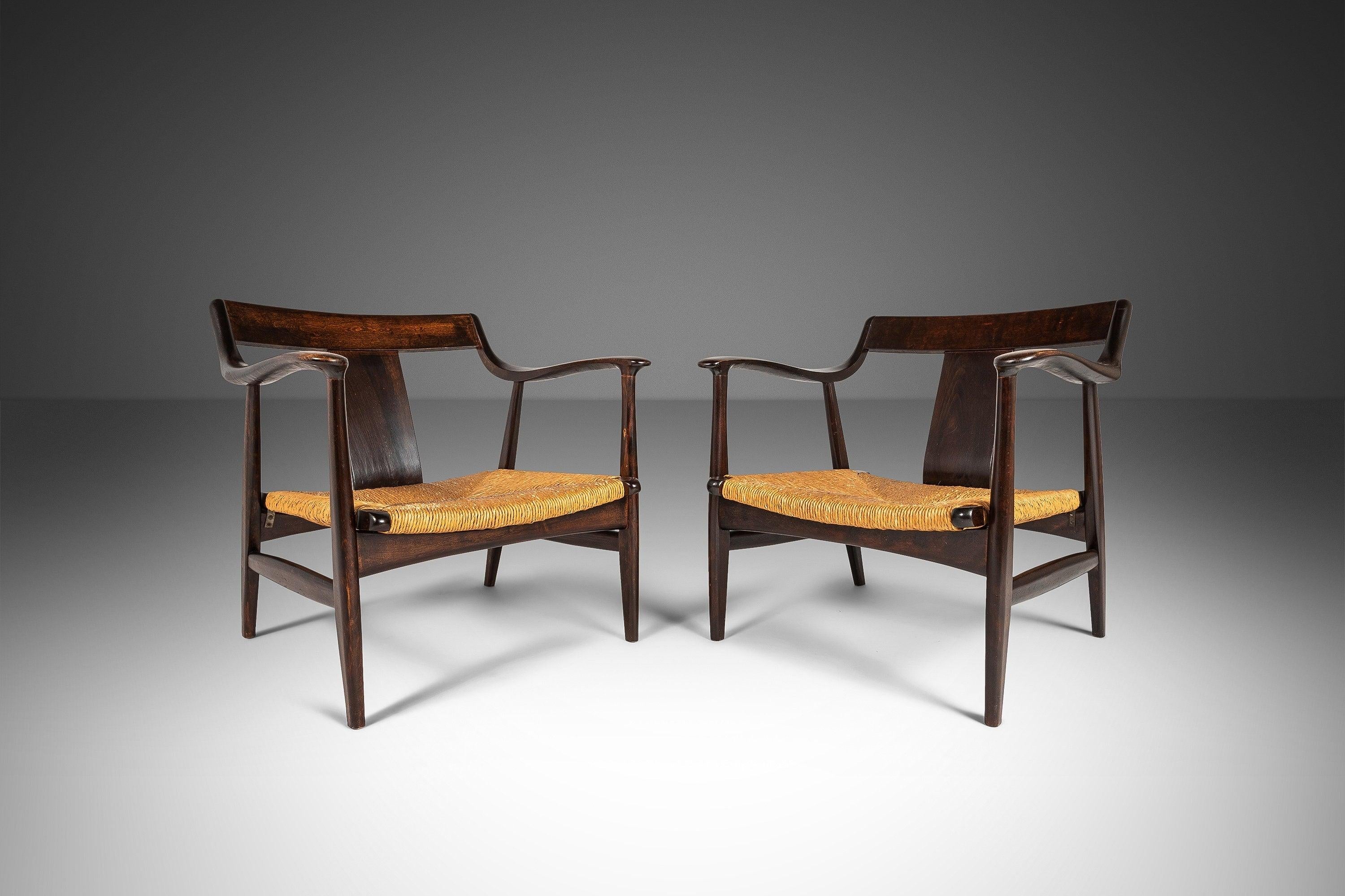 This set of two low profile lounge chairs are alluring, chic and most certainly eye-catching. A rare find originally sold by the Takumi Craft Store of Japan. The frames are constructed from Japanese Oak. The chairs have sleek, curvy arms which are