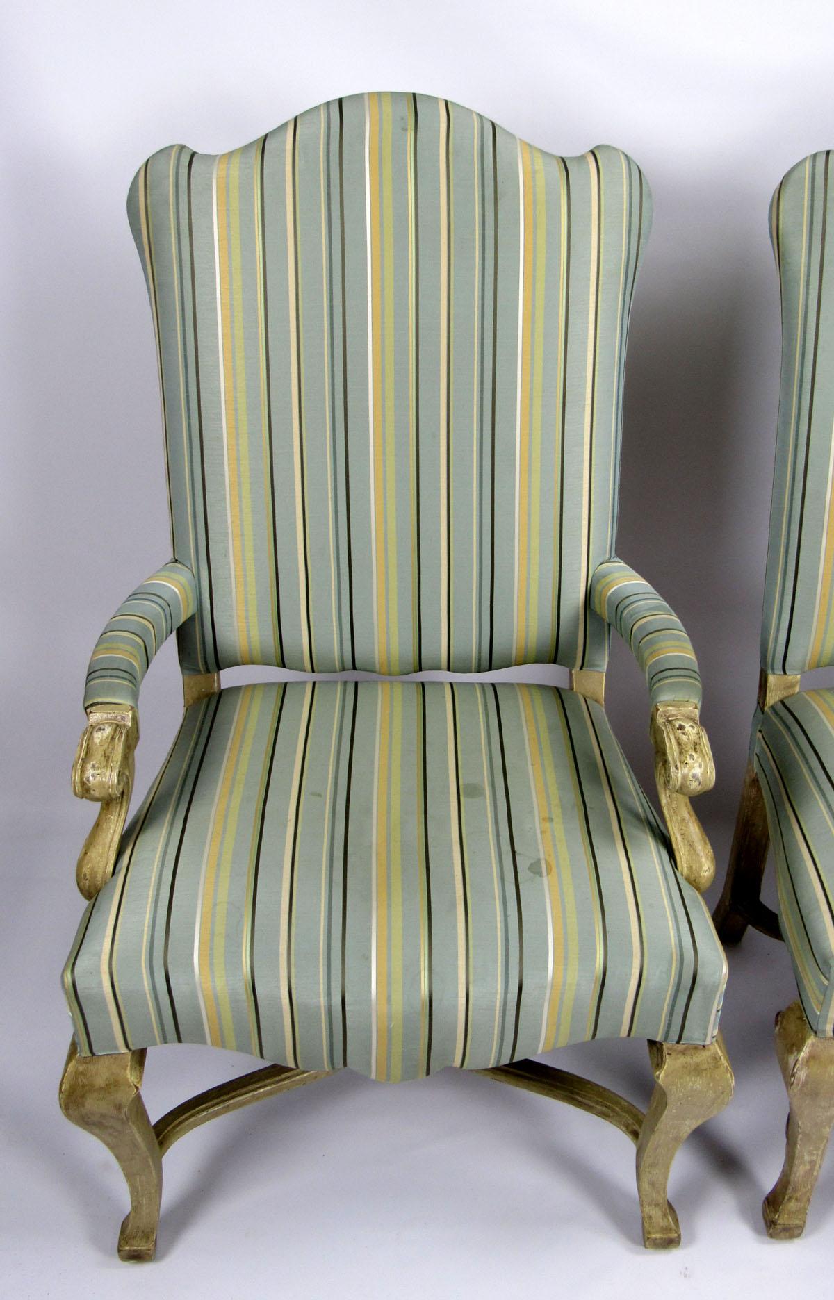 Near pair of 20th century chairs, one arm and one side, hand-carved with a light wood finish, upholstered in a pale blue and yellow striped fabric.

Side chair dimensions: 45½