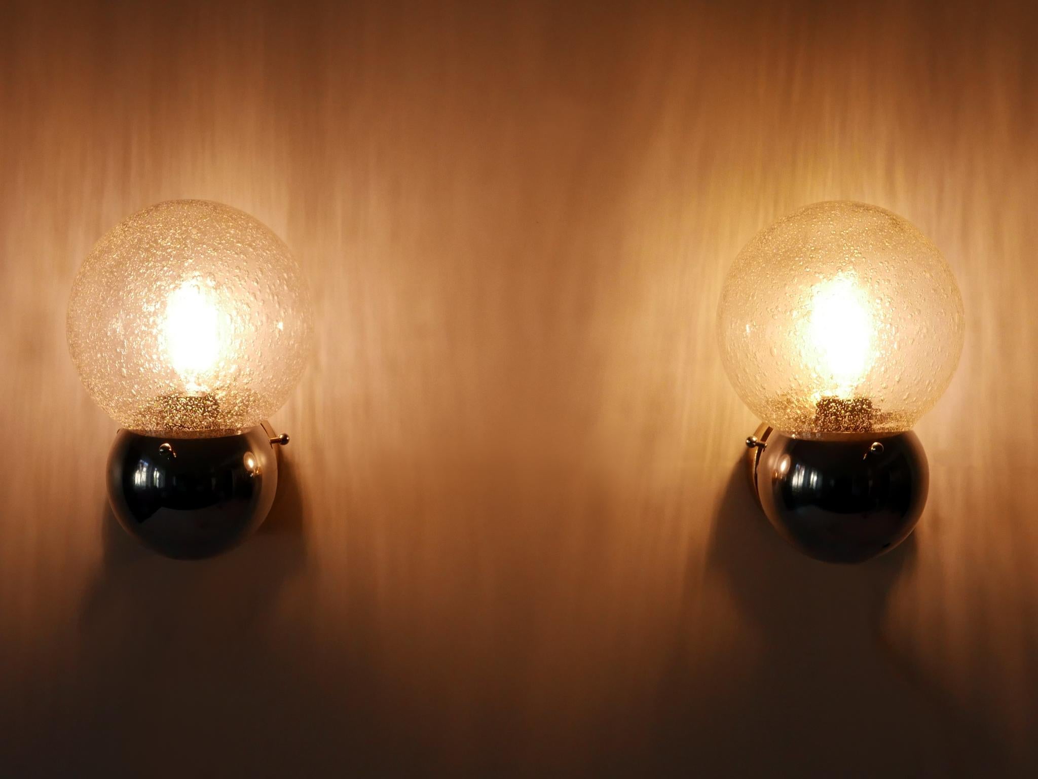 Ensemble de deux magnifiques et très décoratives appliques en métal nickelé et en verre de style Modern-Decor. Conçu et fabriqué en Allemagne, dans les années 1970.

Exécutée en métal nickelé et en verre, chaque lampe nécessite une ampoule à vis E14