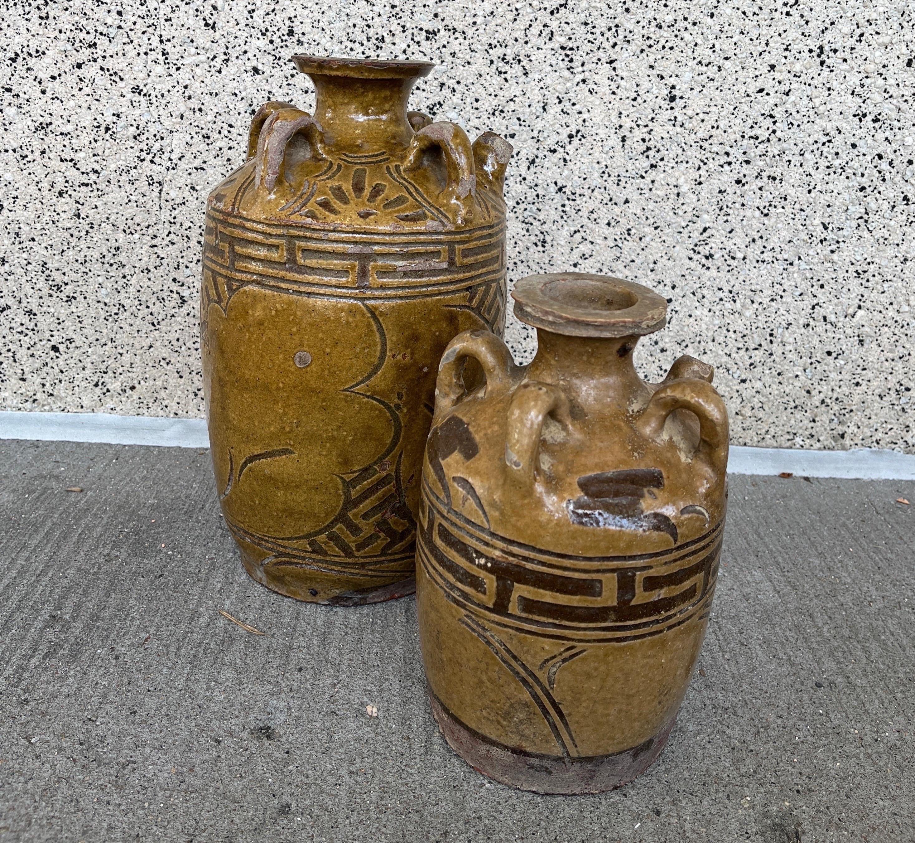 Un ensemble vraiment attrayant et inhabituel de deux jarres à vin antiques en céramique chinoise.  Chaque pièce présente une glaçure similaire, une décoration peinte à la main et un design apparenté, avec quatre anses surmontant chaque jarre.   La