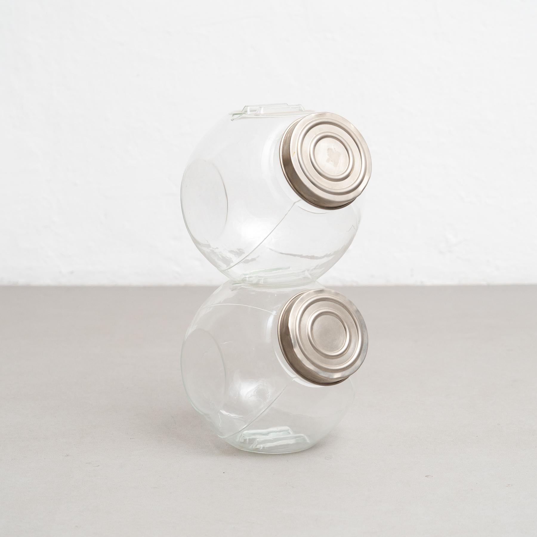 Antique stackable set of two glass containers with a metal cap. 

Step into a realm of refined sophistication with this captivating antique glass container, complete with a gracefully adorned metal cap. Meticulously crafted in Spain around the year