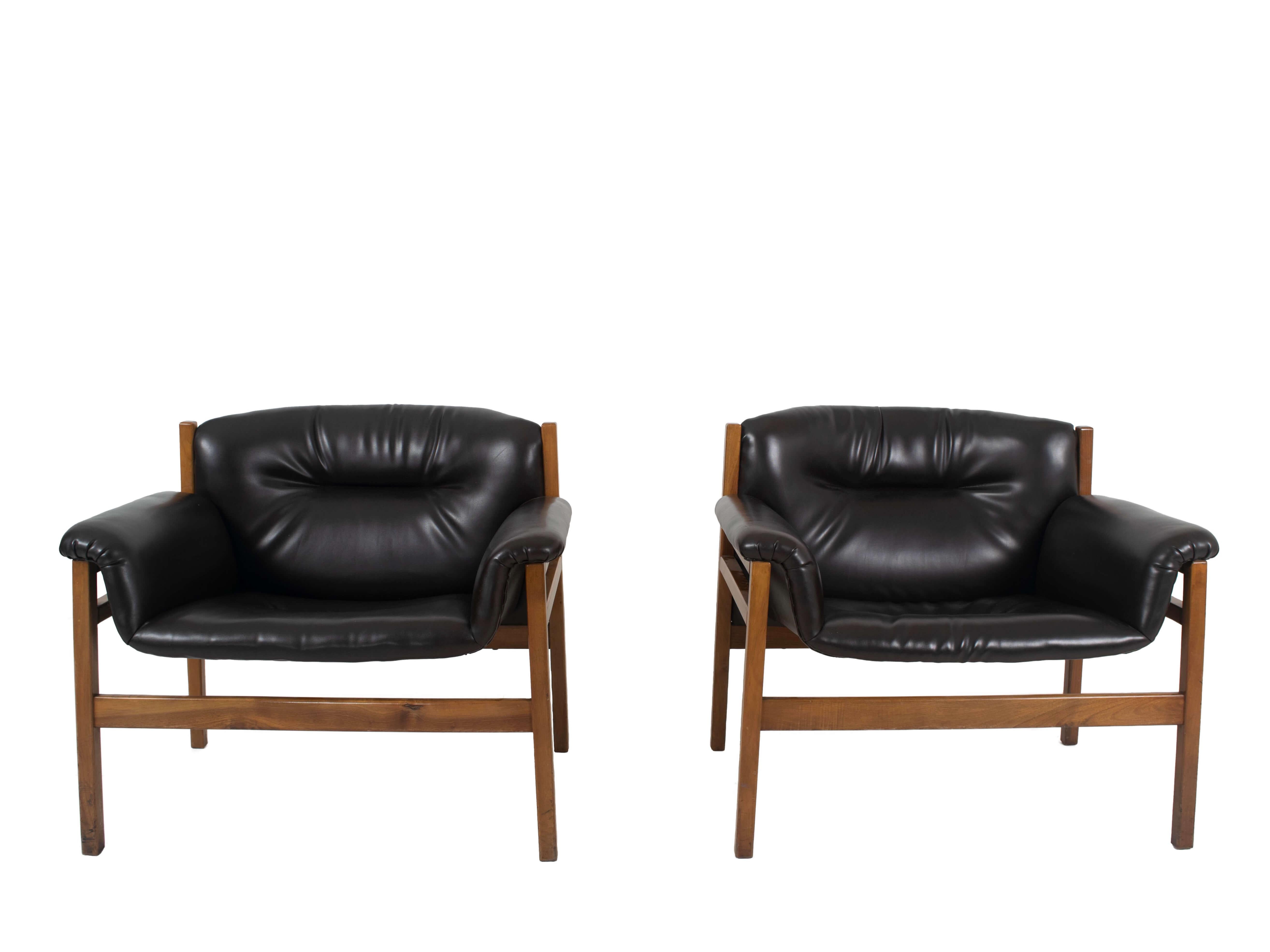 Set of two Italian vintage armchairs in the style of Tito Agnoli, 1960s. These two armchairs in wood and black skai leather are very comfortable. The design is linear and minimalistic, however the use of the round shapes in the cushions gives it a