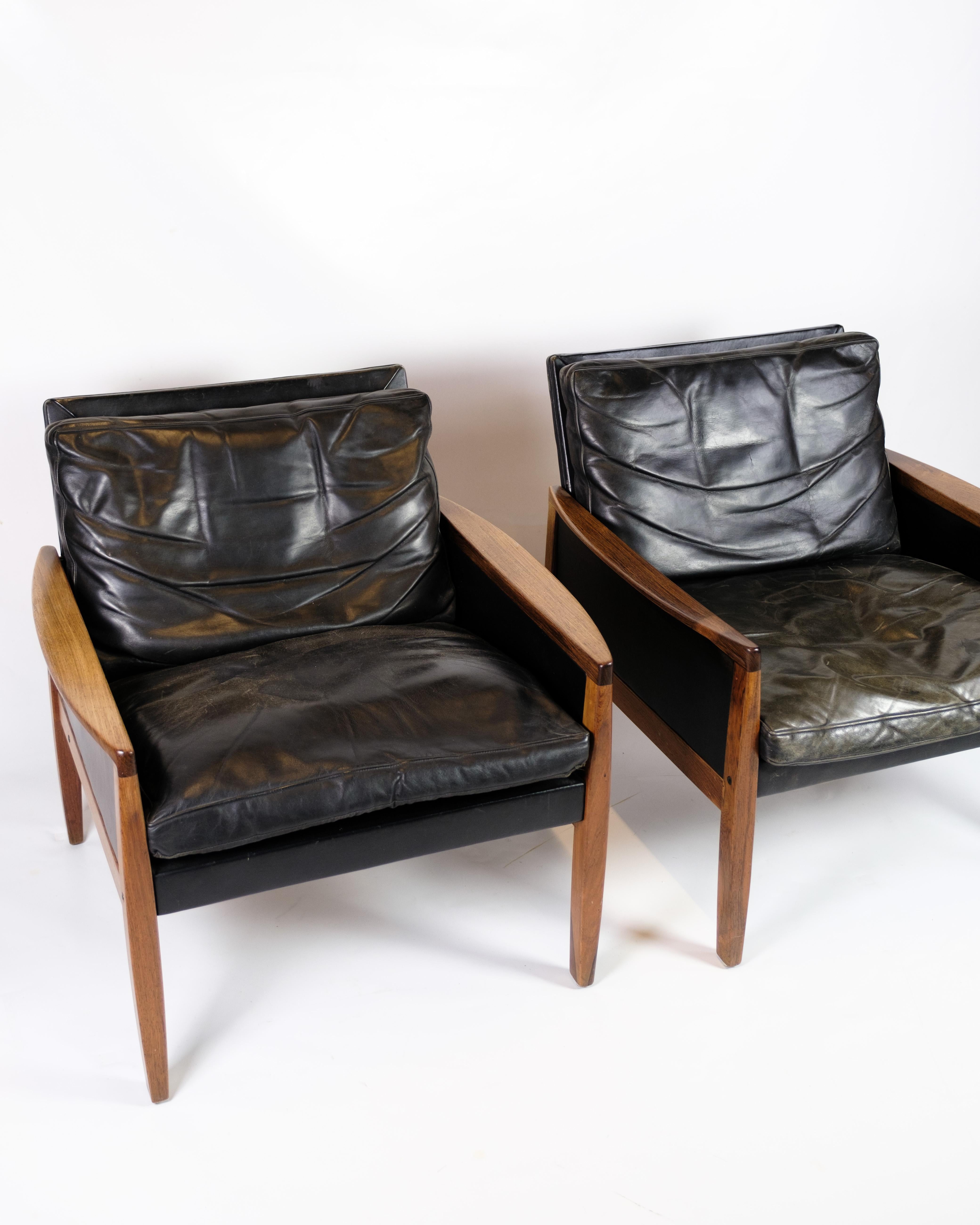 This set of 2 armchairs in rosewood with black leather cushions is a magnificent example of classic Danish design. The rosewood wood, with its deep color and fine grain, gives the chair a unique and luxurious radiance, while the soft, black leather