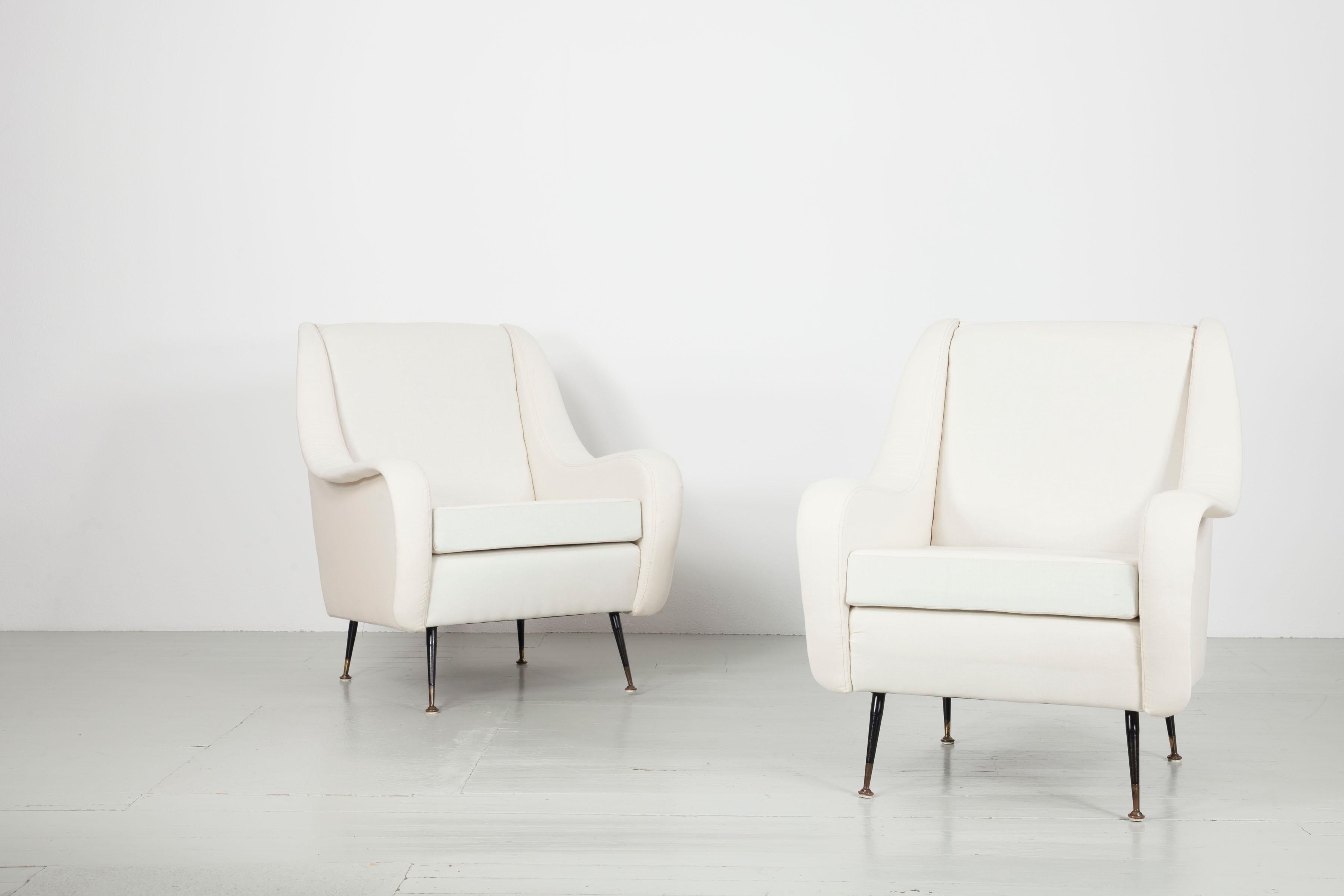 Pair of Armchairs of Italy in 1950s. This design features dominant armrests which define the side lines of the pieces. The Armchairs rest on dainty brass bases following classical italian design traditions. The armchairs were upholstered and covered