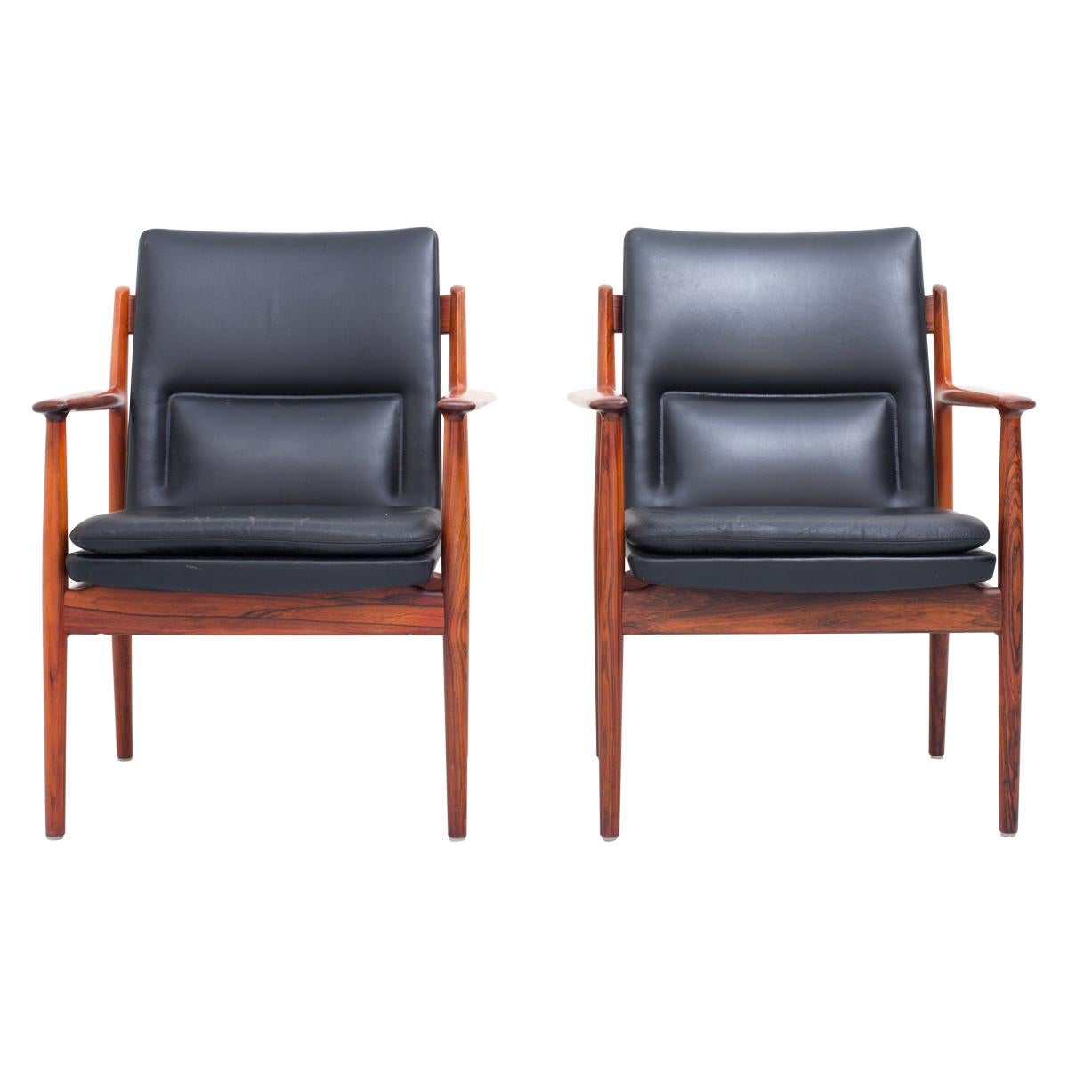 Set of 2 Arne Vodder Armchairs in dark wood and black leather in very good condition. Comfortable set because of the extra built-in lower-back cushions. Good contrast between the vivid wood and the black leather. The black of the grains of the wood