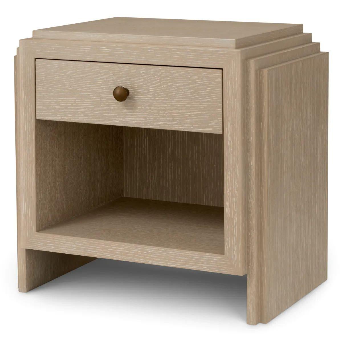 This Art Deco nightstand in washed oak veneer is a refined piece designed to bring warmth, structure, and elegance to any bedroom. With its soft tones and distinctive bronze finish, the nightstand blends natural materials with subtle metallic