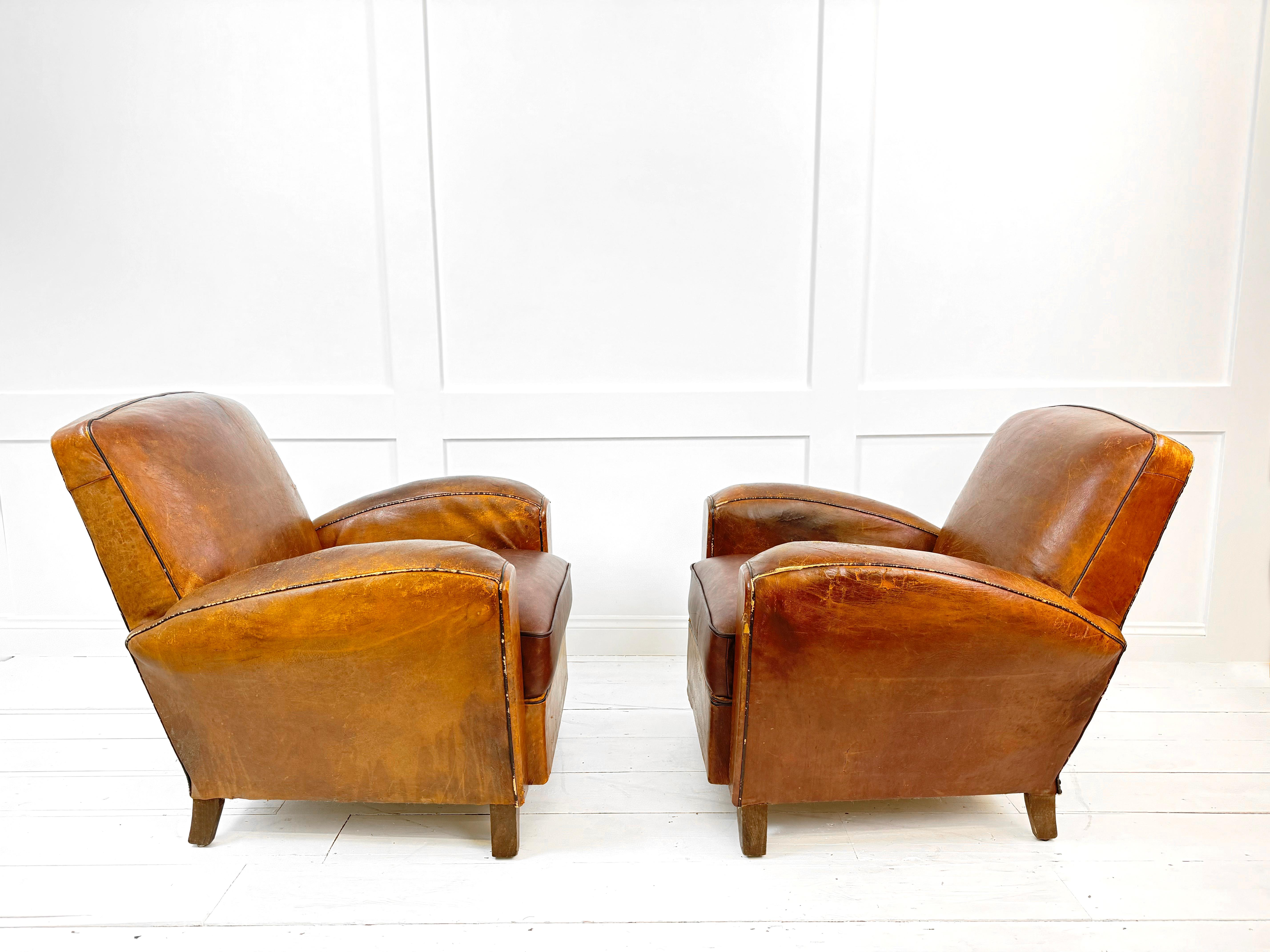 The quintessential of French Art Deco style - the Tan Leather Club Armchairs from the 1930's. This pair of exquisite armchairs exudes luxury and sophistication, showcasing the elegance of the era. Crafted from the finest tan leather and featuring