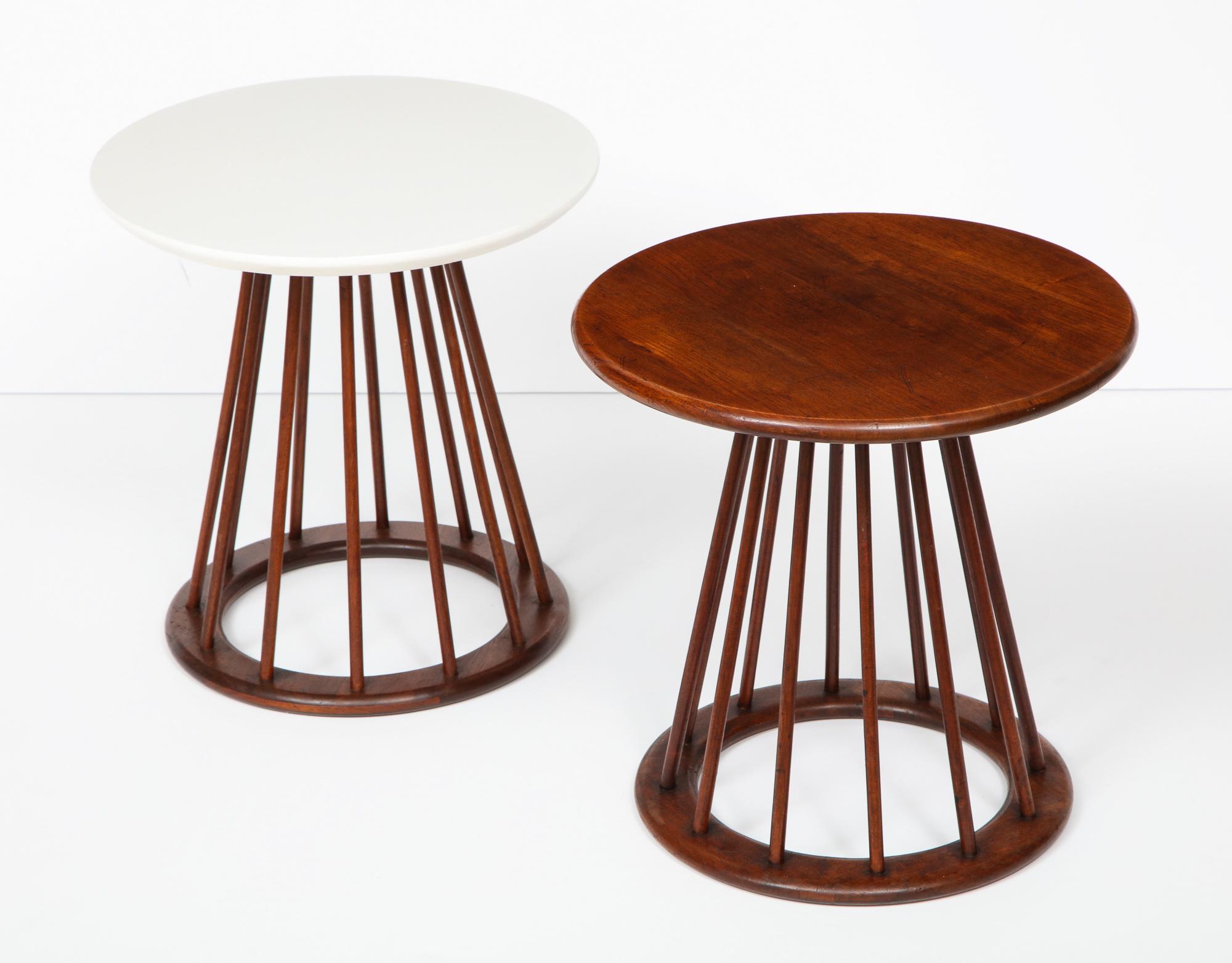 Set of two round spindle leg side tables designed by Arthur Umanoff and produced by Washington Woodcraft, circa 1950's. One table has a walnut top and walnut base; the other has a walnut base with a white micarta top and white painted edges. Both