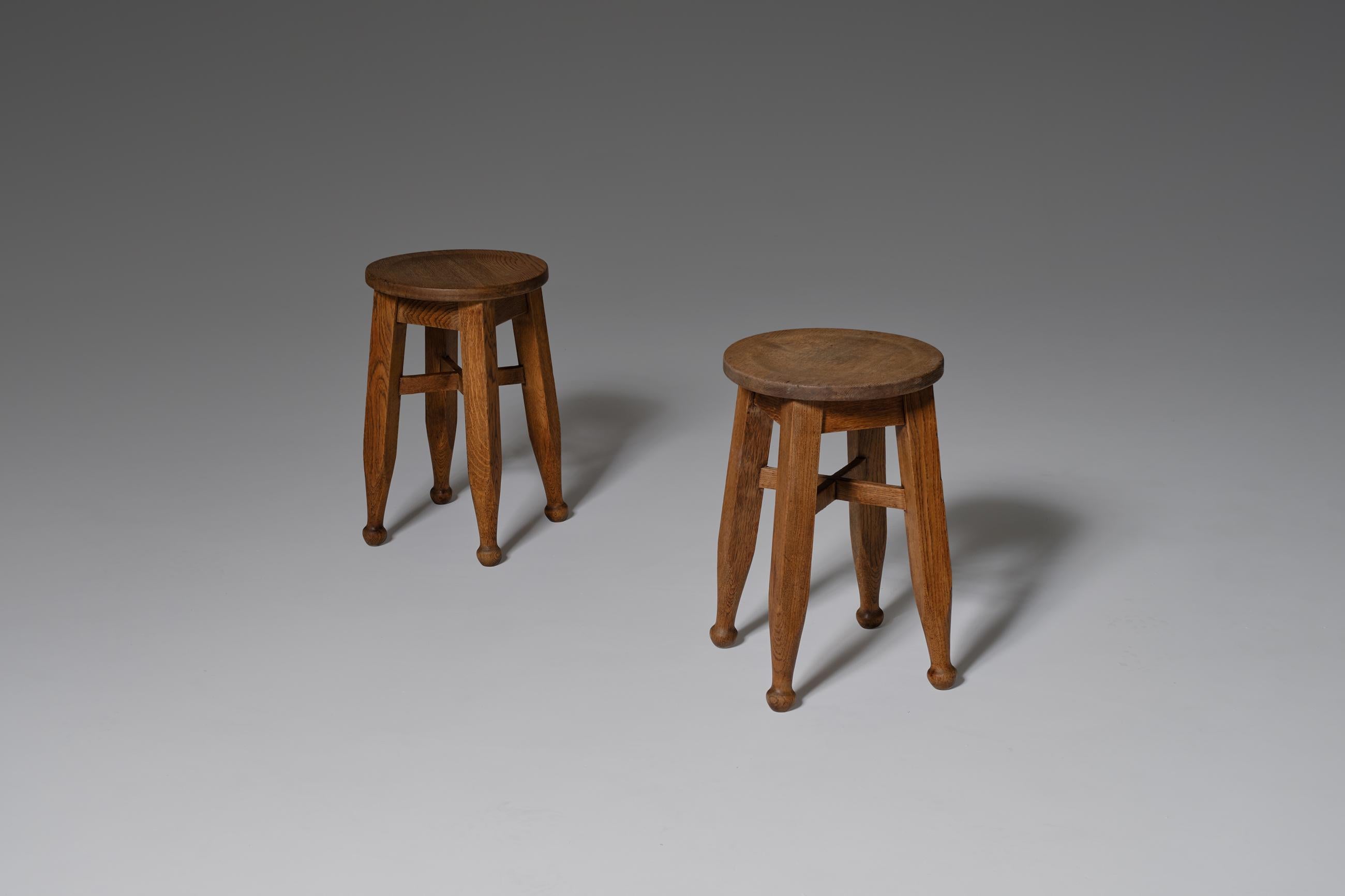 Pair of Arts & Crafts stools by Harold & Sheldon LTD Birmingham, England, early 20th century. Rough yet refined pair made in solid oak. The stools have nice crafted details such as the ball shaped legs, the cross construction and the nicely carved