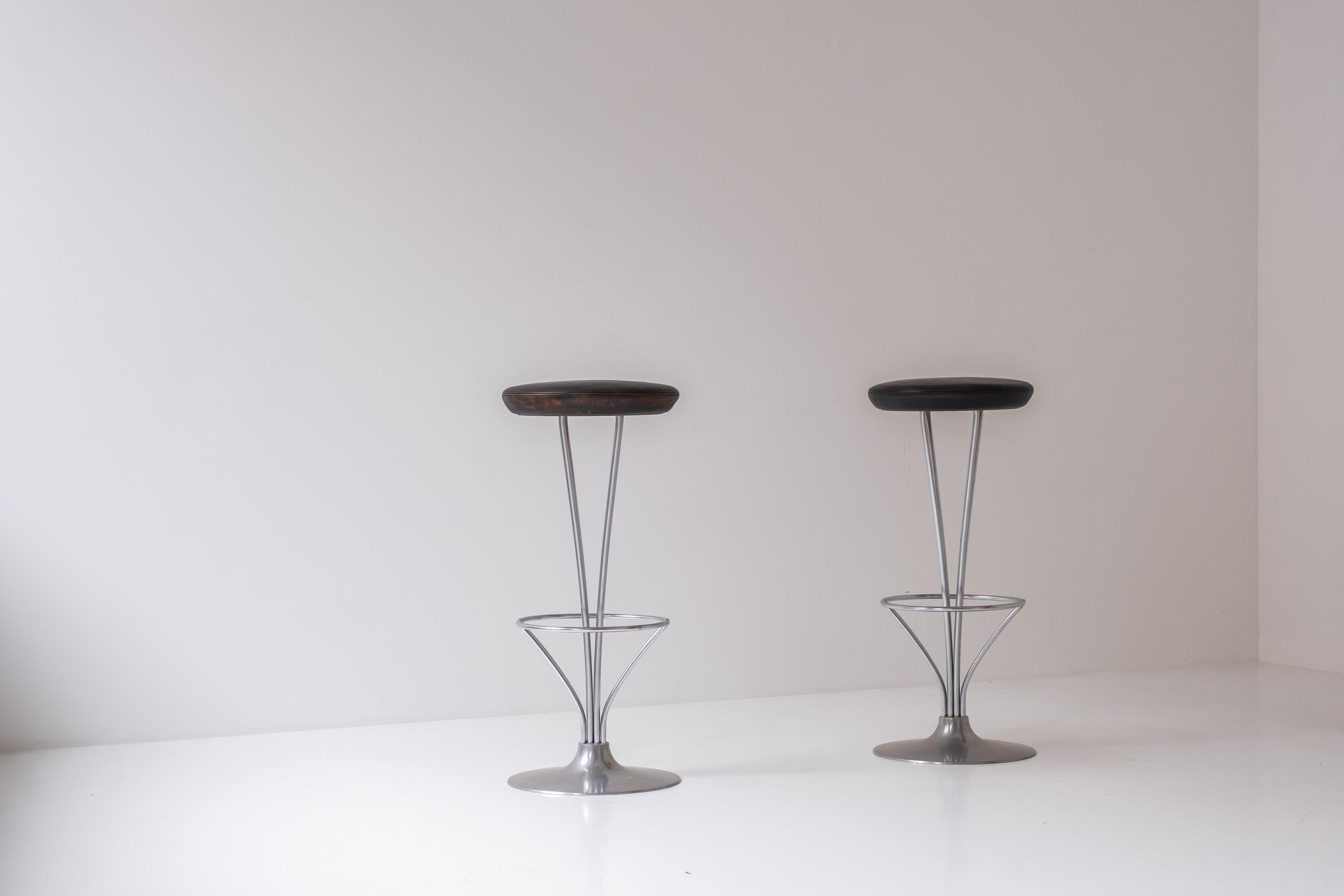 Lovely set of two bar stools by Piet Hein for Fritz Hansen, Denmark, 1960s. These stools have chrome-plated frames and a brushed aluminum base with its original brown leather upholstery with a nice soft overall patina. Labeled underneath.