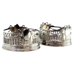 Set of two bottle bottoms in cut silver w/ monogram cards
surrounding strips