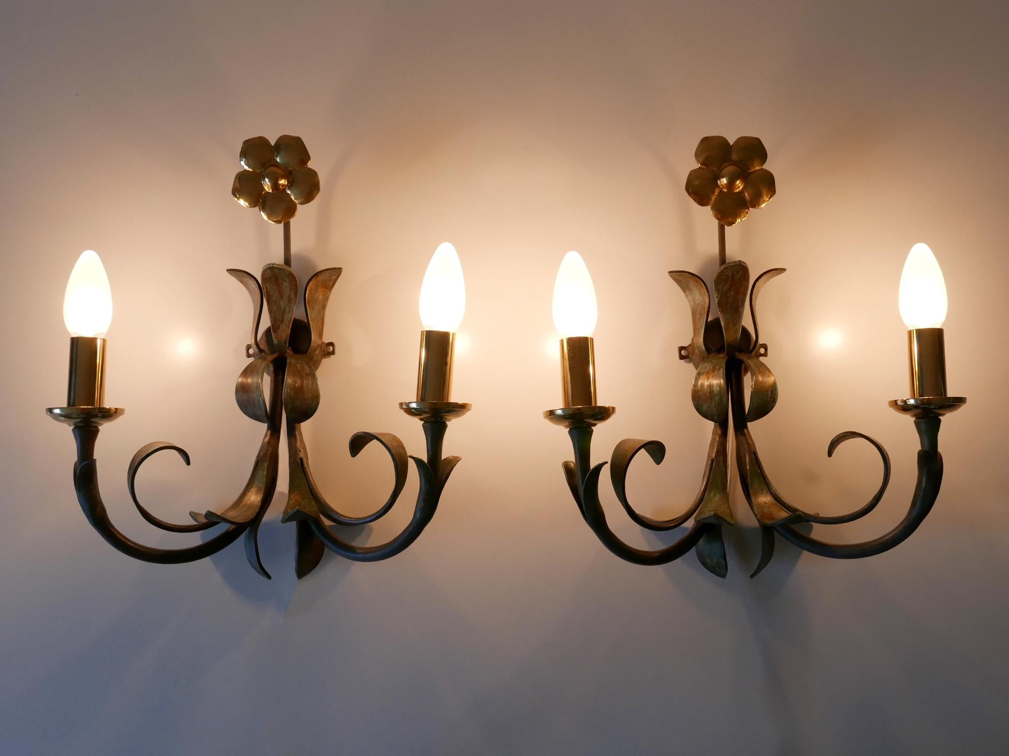 Set of two lovely and decorative Florentine sconces. Designed & manufactured by Hans Möller, Germany, 1970s. Manufacturers label reverse.

Executed in brass and patinated metal, each fixture is executed with 2 x E14 / E12 Edison screw fit bulb