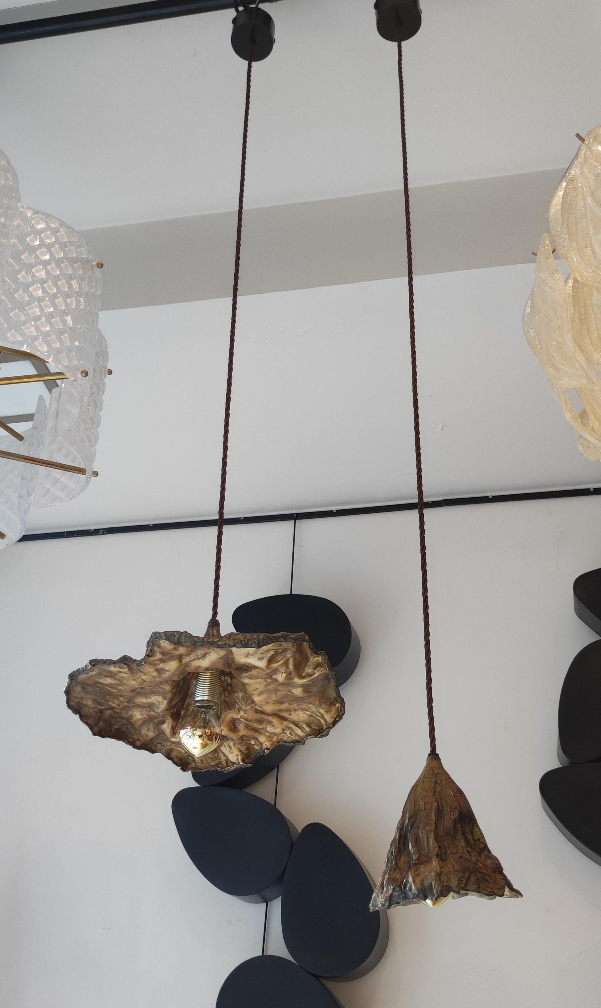 Two different bronze light suspensions in the shape of a faded leaf, provided with a golden bulb. Golden interior.

Dimension: H 16 x 20 x 12 cm and H 10 x 30 x 26 ) without the cord.
Max H: 160 cm (can be shortened).

3 pieces of each model