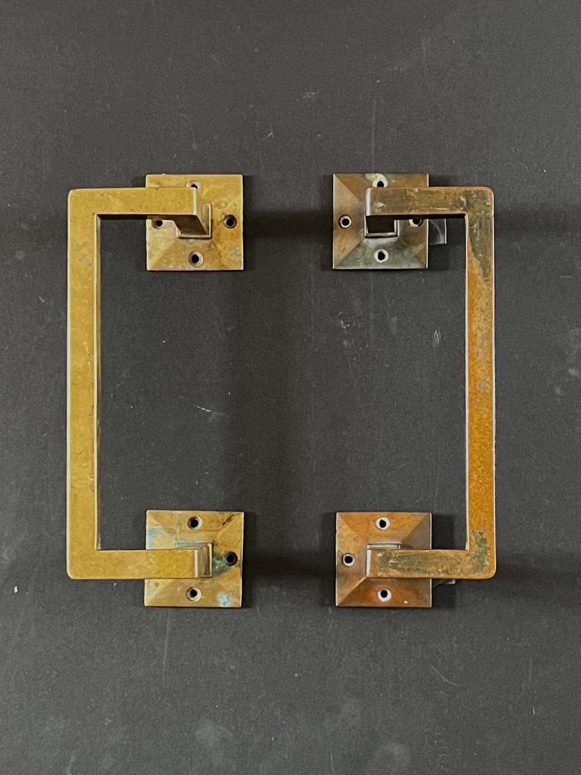 A pair of angular bronze door handles, each with square mounting plates. First half twentieth century, found in Denmark.

The handles are a simple design, made from bronze with a warm aged patina, which we have left as found. The handles each have