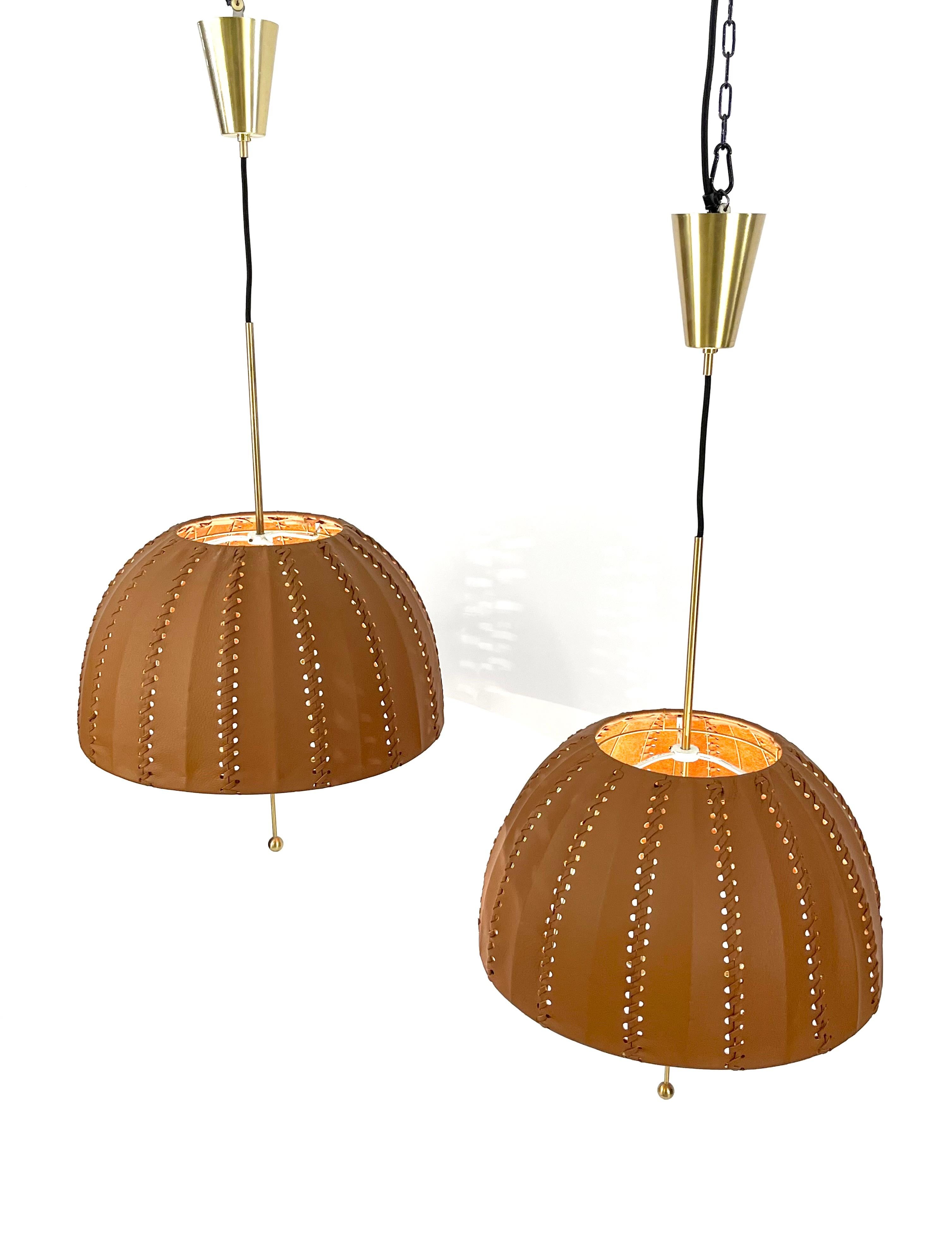 Beautiful original 1960s pendant lamps “Carolin” model T549 by Hans-Agne Jakobsson for Markaryd Sweden.
Refurnished shades in brown leather. 
The height of the lampshade is adjustable.
