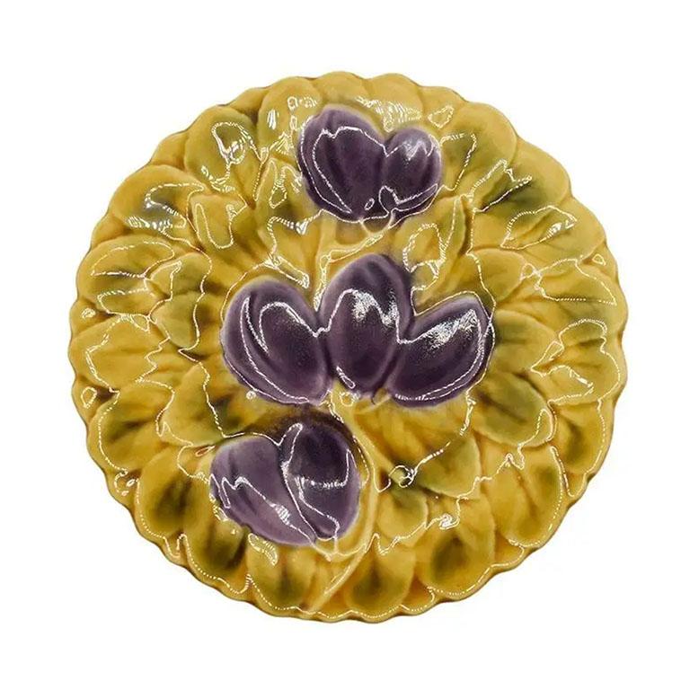 Un ensemble de deux assiettes en majolique poluychrome de mouvement esthétique avec des motifs de fruits par Sarreguemines France. Chaque assiette en céramique est ronde et décorée de manière colorée avec un motif de fruits en violet, vert et rose.