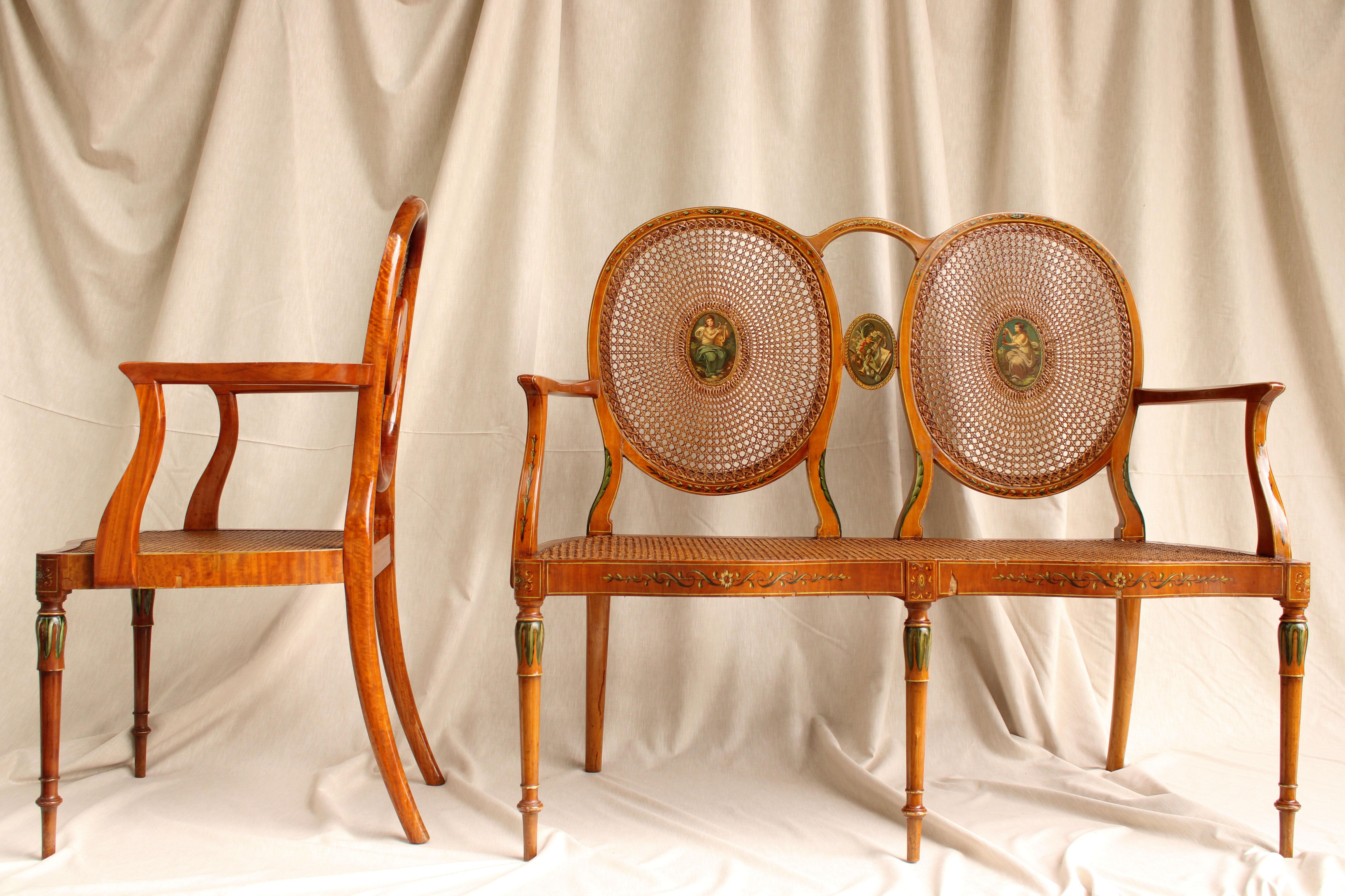 This 19th century French furniture set is truly remarkable and has a unique and elegant style. The set includes two chairs and a settee, all made of natural cane and with medallions painted to the taste of Angelica Kauffmann, an 18th-century Swiss