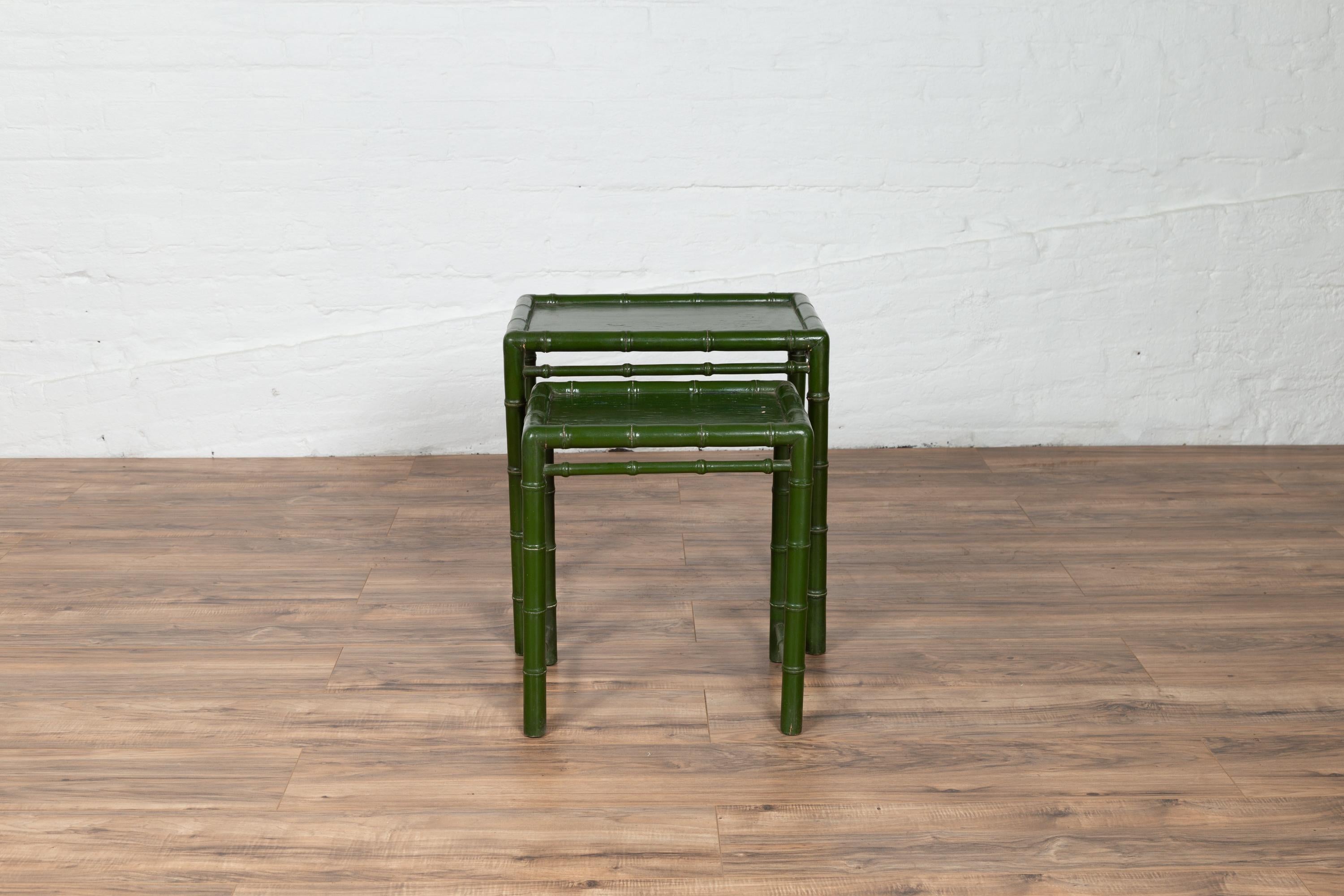 A set of two Chinese vintage bamboo nesting tables from the mid-20th century, with green lacquered finish and side stretchers. Born in China during the midcentury period, each of these two nesting tables features a bamboo structure, supporting a