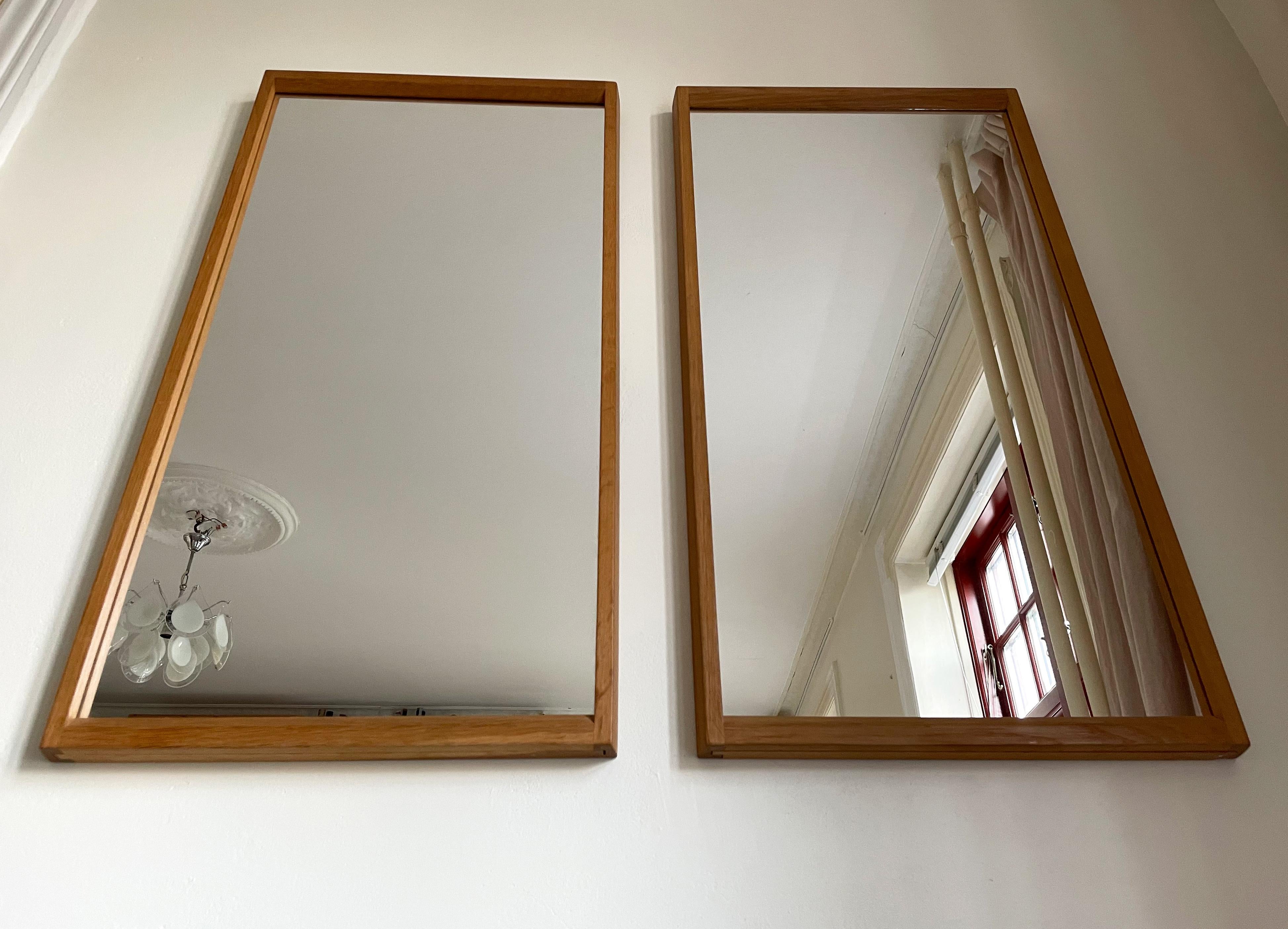 Rare set of two classic, simple Danish modernist mirrors of the model no. 143 that have stayed together since production in the early 1960s, thus same color and patina to the wood. Elegantly profiled rectangular oak frame with beautiful finger