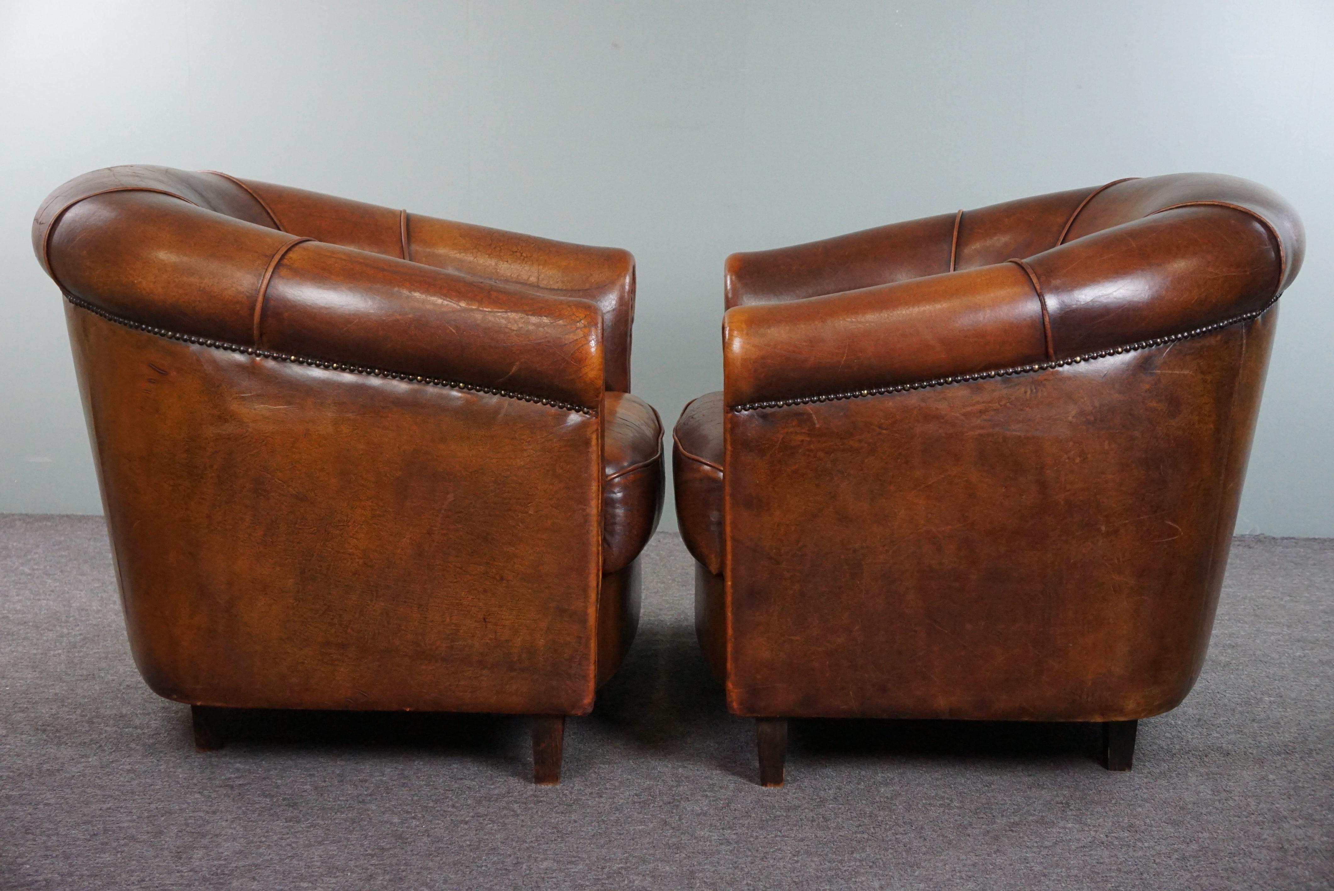 Offered is this lovely and luxurious set of two club armchairs made of sheep leather in a beautiful warm dark color. Nothing is more beautiful than a set of two matching sheep leather club armchairs in your room or office to complete the look. This