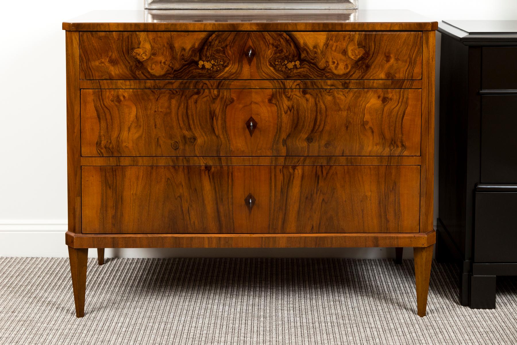 Two stunning and complimenting Biedermeier style walnut book matched veneer chests comprised of  three working drawers opening each with a key used as a pull and finishing on chamfered straight and tapered legs. Both restored at the same time