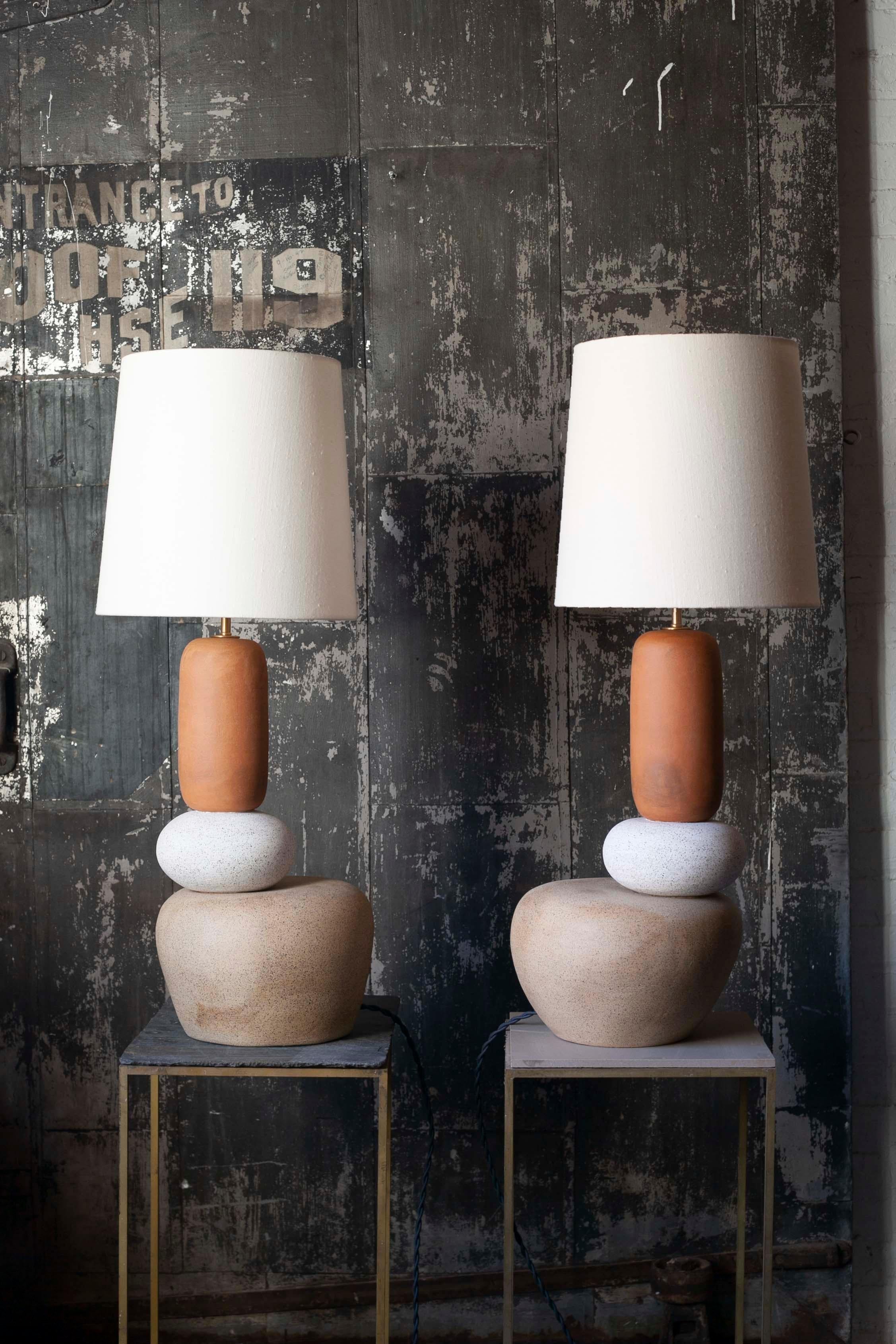 Pair of one of a kind ceramic lamps, thrown on the potters wheel and assembled by hand. The lamp base is comprised of two different clay bodies and features a raw, unglazed ceramic surface to highlight the texture of natural clay. These pieces are