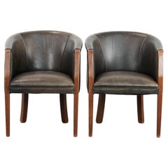 Set of two cowhide and wooden tub chairs with a sturdy colour schem
