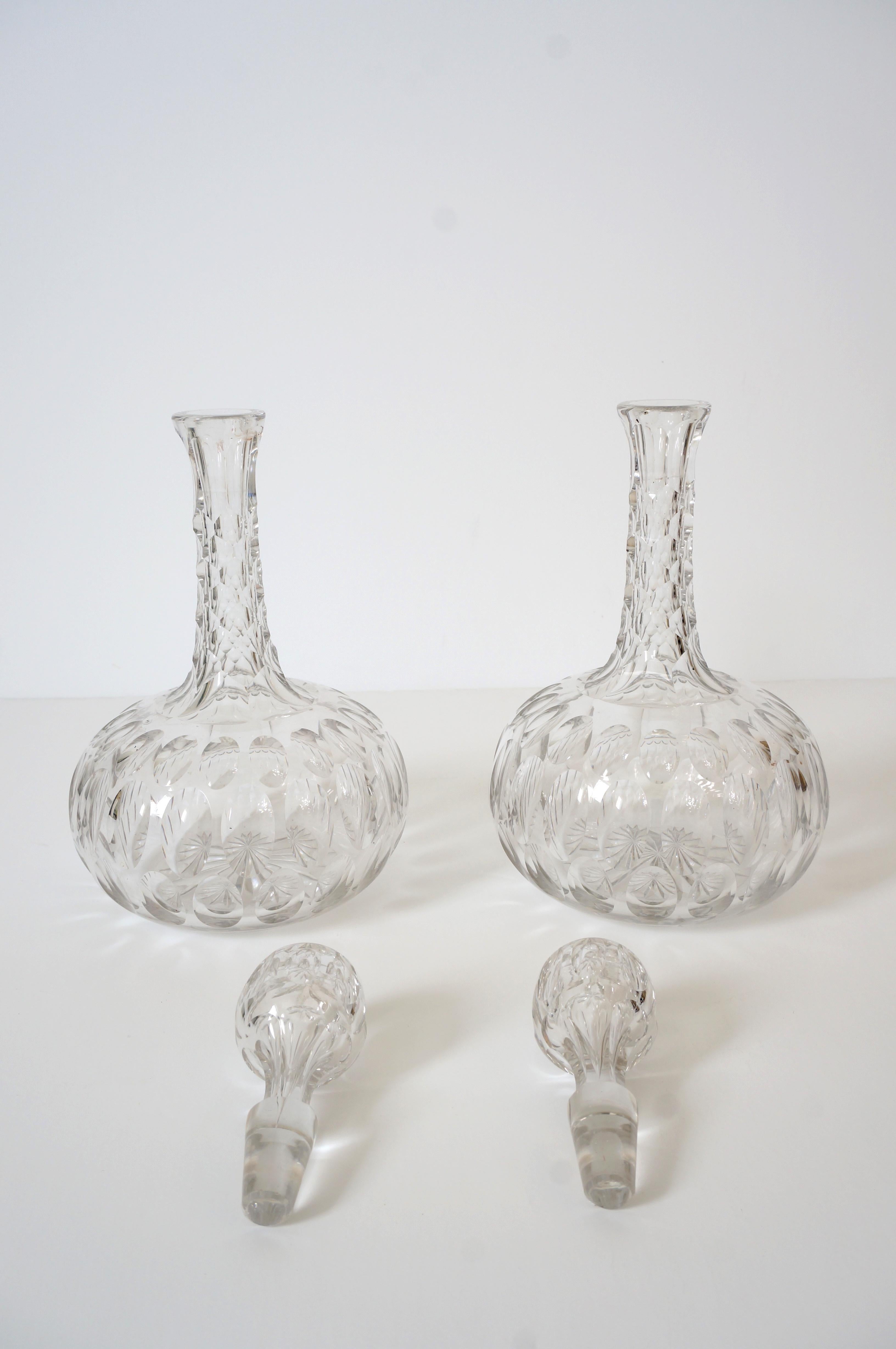 This stylish set of two English Regency revial form cut crystal decanters will make a handsome addition to your barware collection. The optic cameos catch the light beautifully and the cut grip on the neck makes for a secure handle on the pieces.