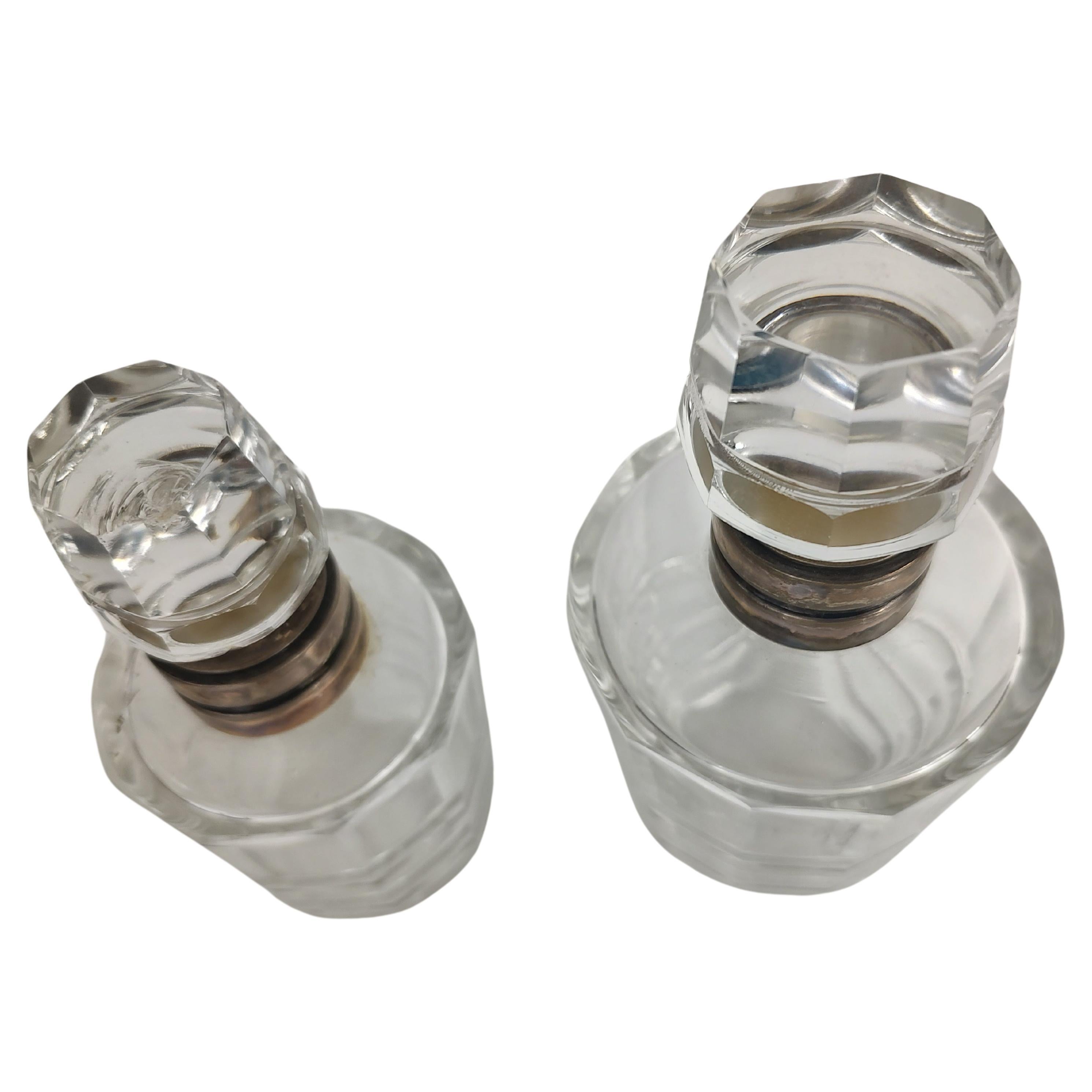 Favolosa coppia di bottiglie da comò in vetro tagliato con collari in argento. La bottiglia più piccola ha una scheggiatura sul tappo. A parte questo, sono in ottime condizioni vintage con un'usura minima. Venduto e prezzato come set.
