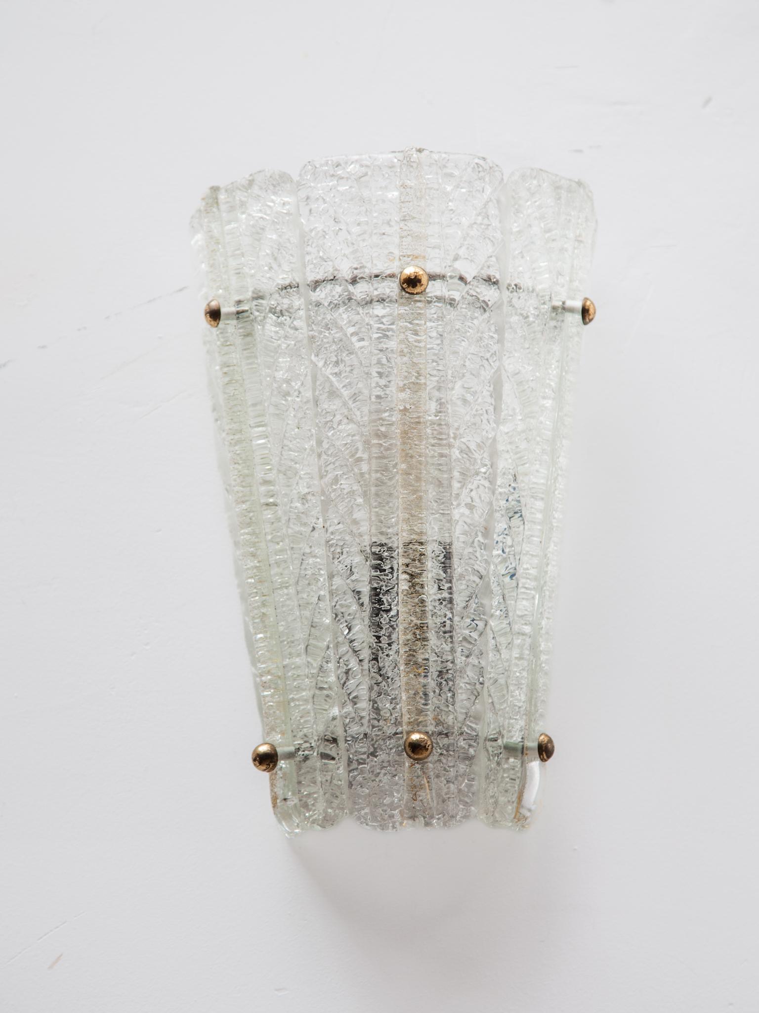 A pair of mid-century wall-lights, sconces with clear ice glass pattern made by Doria Leuchten, Germany, manufactured, circa 1970. 
High quality and in very good condition. Cleaned, well-wired, and ready to use. Each sconce requires 1 x E14 small