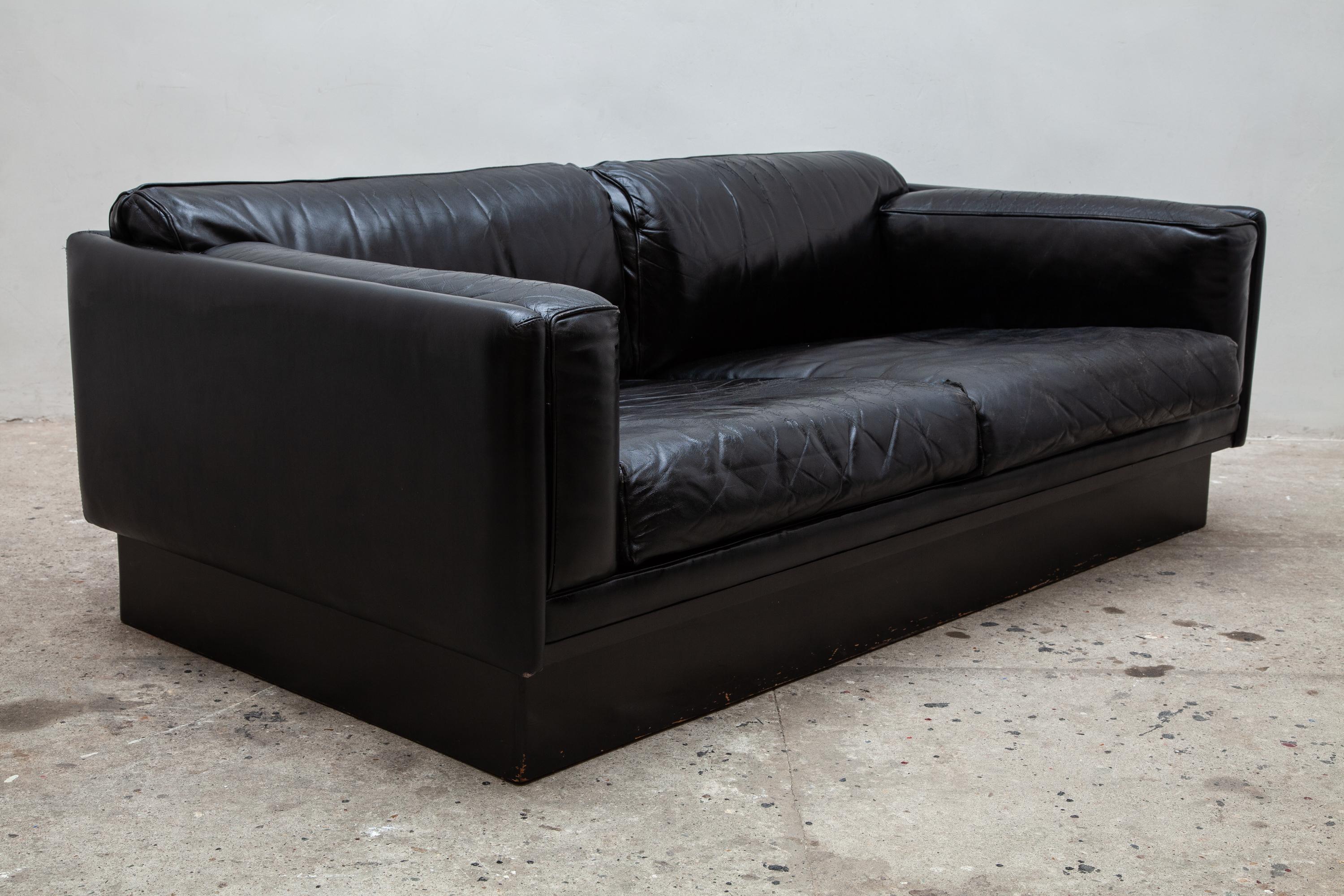 Stylish 1970s black leather couche, loveseat.
This Belgian design features a platform base, metal ball casters and wood lattice support for the seat.
Soft durable leather with vintage patina. Bolster pillows for added design and comfort.
   
