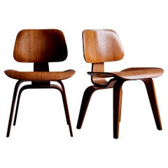 Satz von zwei Eames DCW-Loungesesseln aus Nussbaumholz für Herman Miller, USA, 1950er Jahre