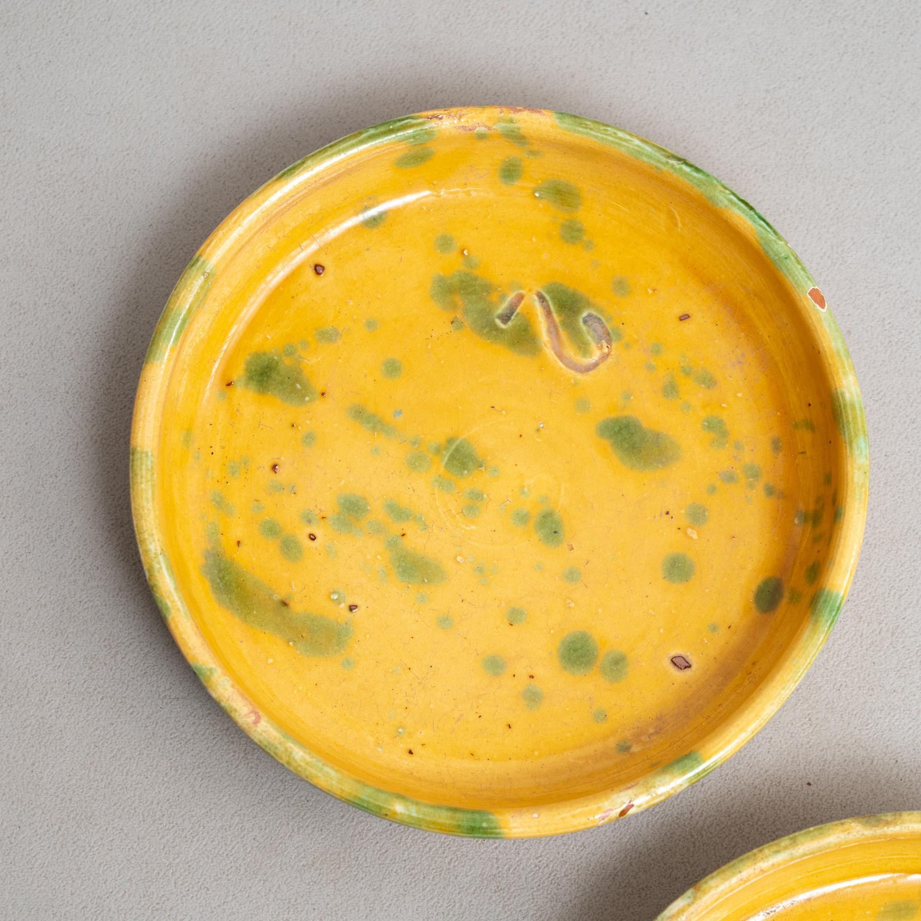 This set of two yellow ceramic plates with charming green speckles evokes the essence of early 20th-century traditional folk pottery. Each piece, carefully hand-painted, reflects the craftsmanship of an unknown artisan in France, who skillfully
