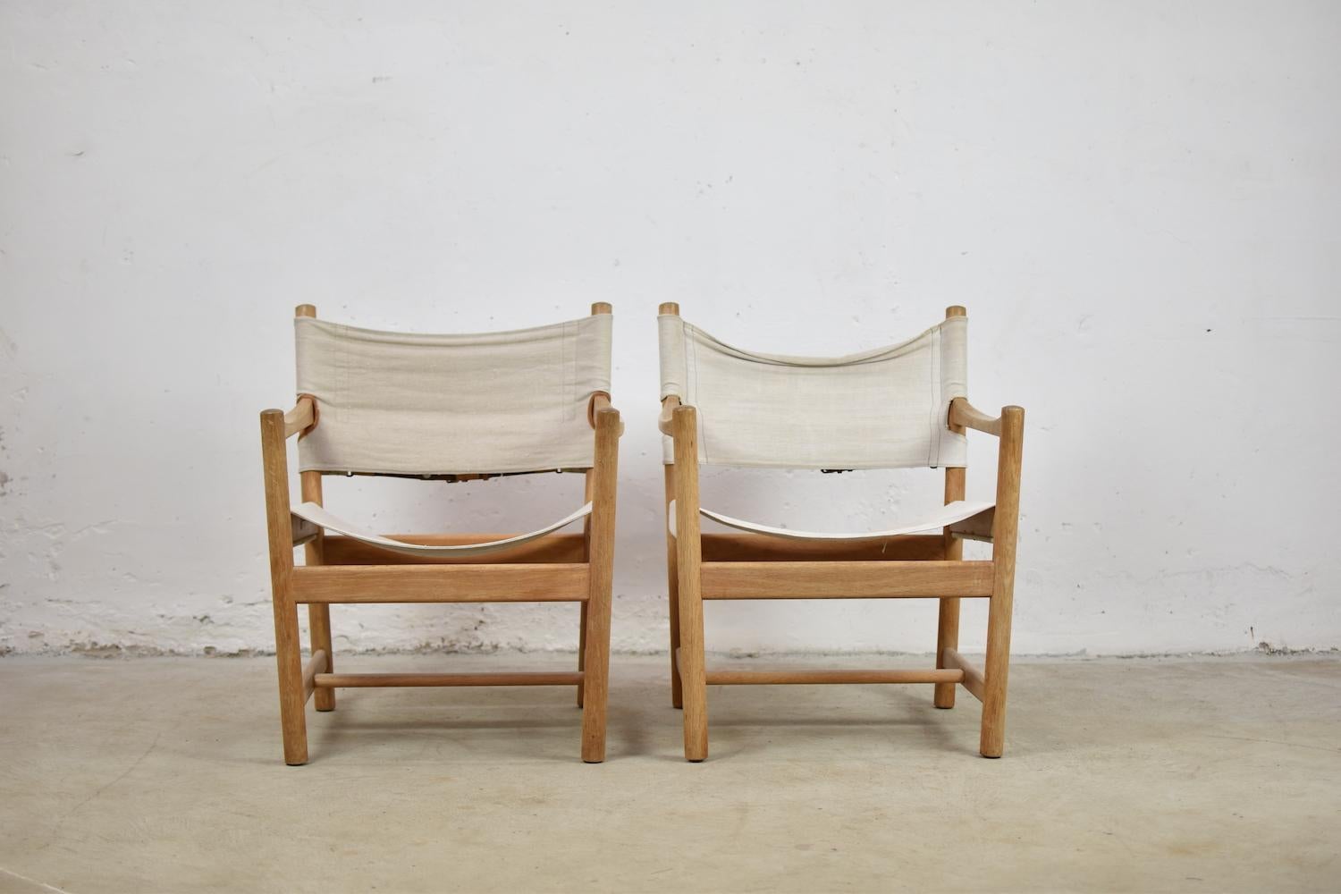 Set of two easy chairs by Ditte and Adrian Heath for FDB Møbler, Denmark, 1960s. These chairs features a tapered frame made of oak and seats and back made of canvas with cognac leather straps. Visible signs of age and wear, but overall in very good
