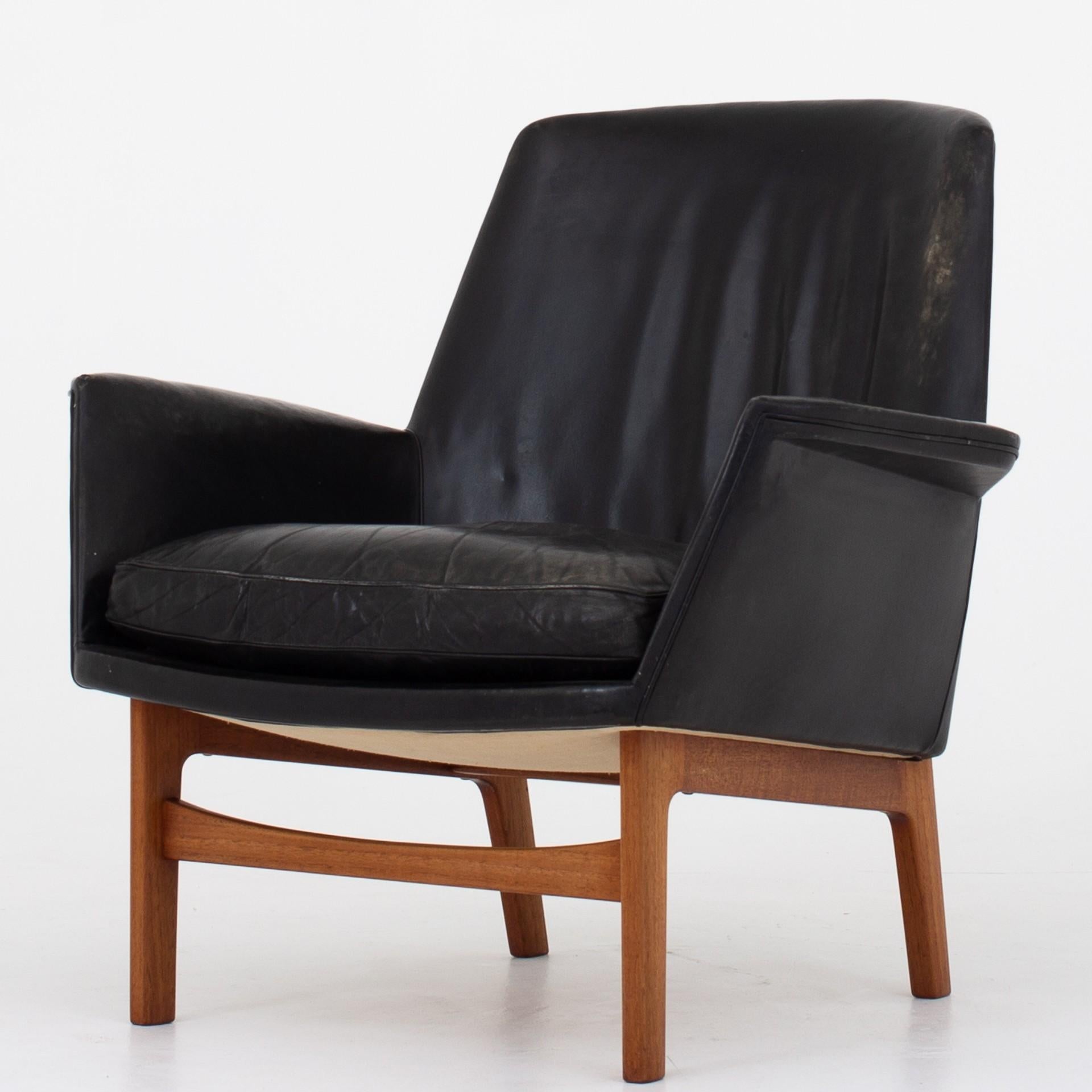 Set consisting of two easy chairs and ottoman in patinated black leather and teak frames. Rare set. Maker Thorald Madsen, 1950.