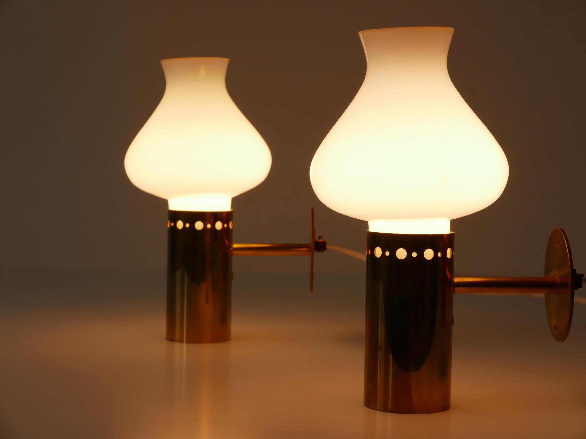 Ensemble de deux élégantes et très décoratives appliques ou fixations murales en forme de tulipe, de style Modern-Decor. Conçu et fabriqué en Suède, dans les années 1950.

Réalisé en laiton et en verre opalin, chaque luminaire nécessite une ampoule