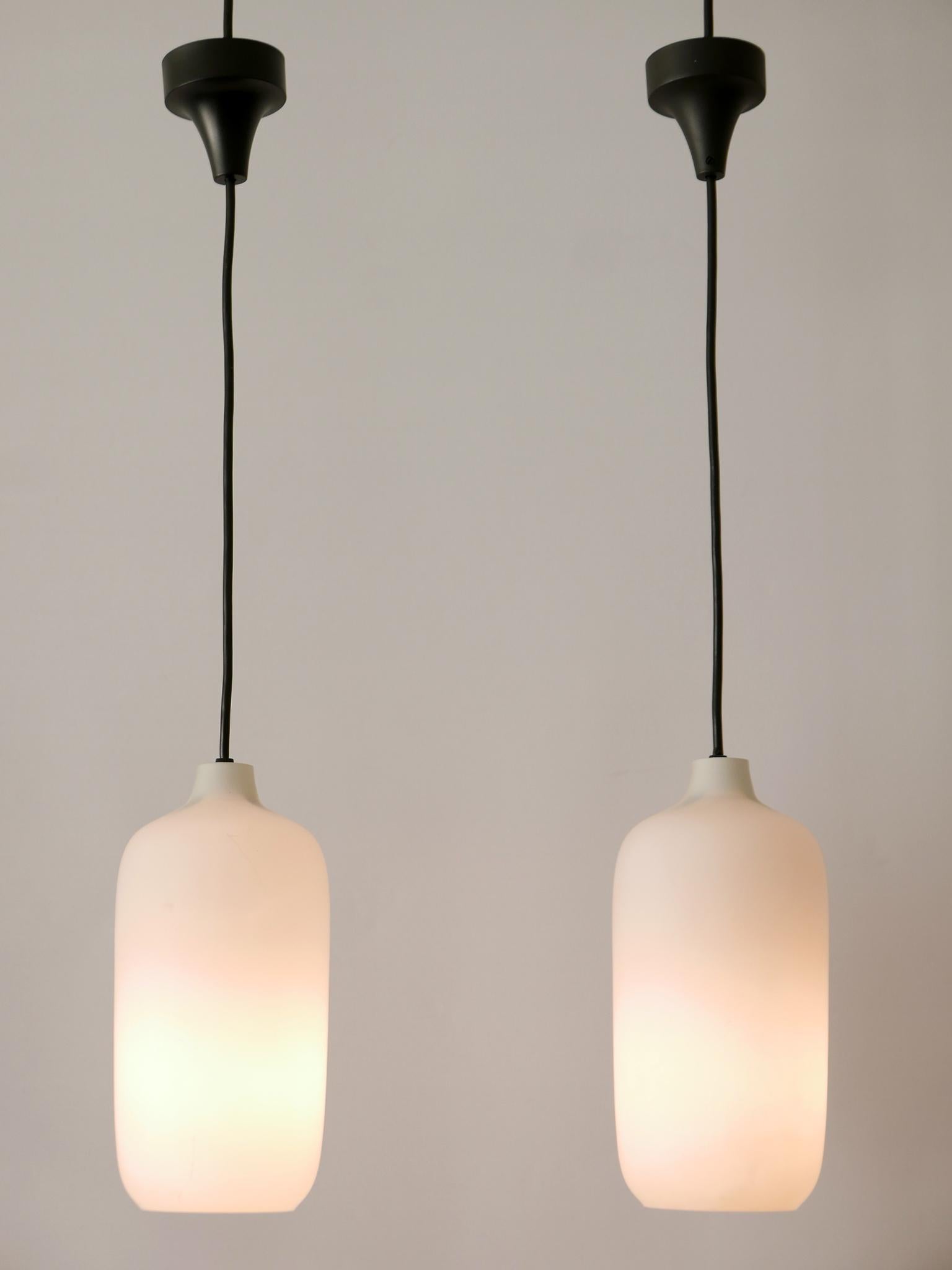 Set of two lovely and elegant Mid-Century Modern opaline glass pendant lamps in organic shape. Designed and manufactured in Scandinavia, 1960s.

Executed in opaline glass, each pendant lamp has 1 x E14 / E12 Edison screw fit bulb socket, is wired