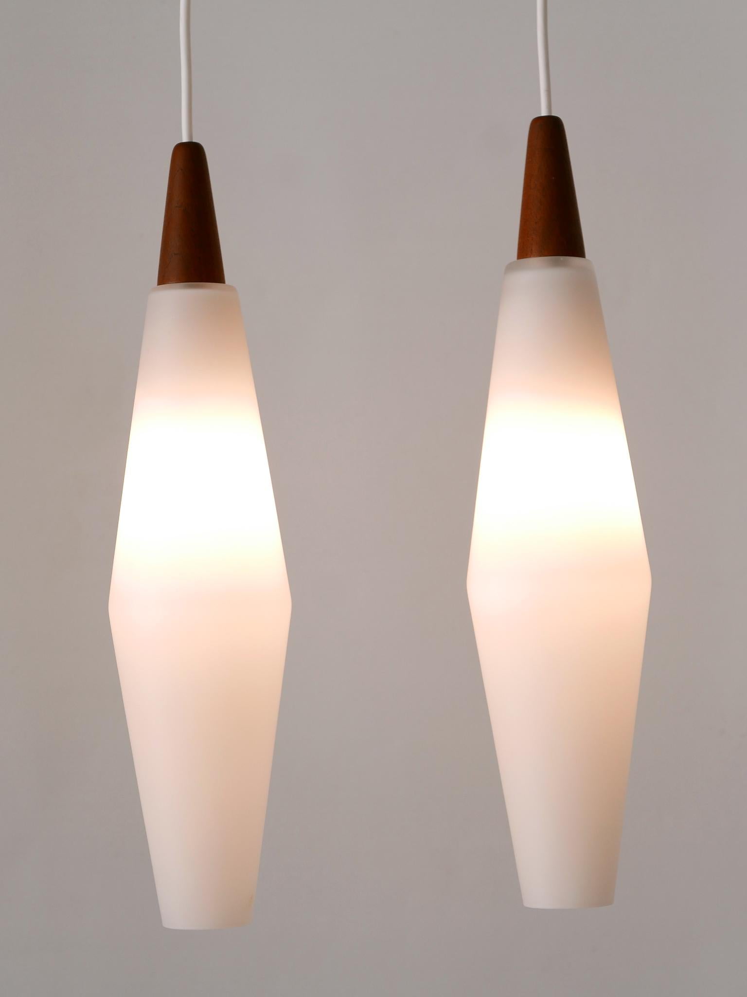 Set of two lovely and elegant Mid-Century Modern opaline glass & teak pendant lamps in organic shape. Designed and manufactured in Scandinavia, 1960s.

Executed in opaline glass & teak wood, each pendant lamp is executed with 1 x E14 / E12 Edison