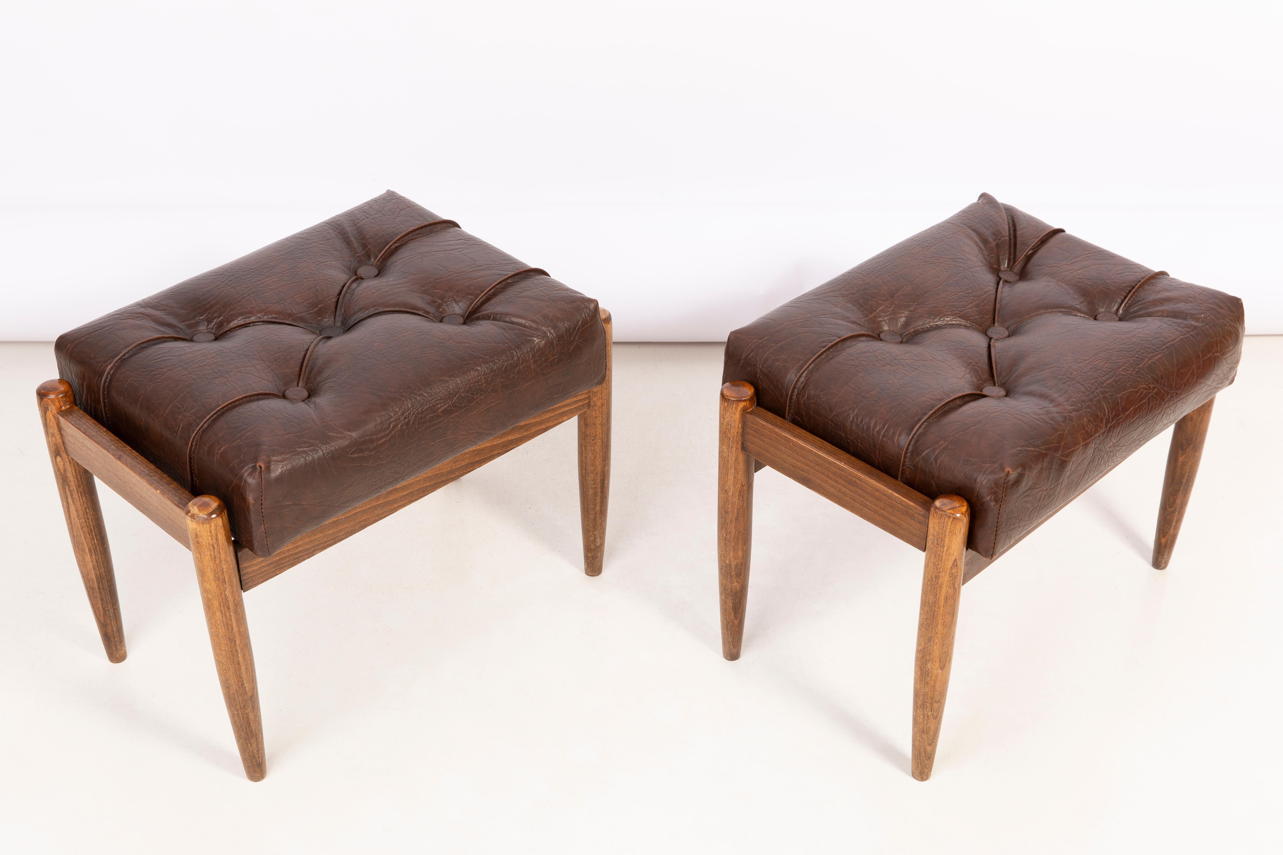 Taburetes de principios de los años sesenta. Bonito cuero sintético marrón de alta calidad. Los taburetes constan de una parte tapizada, un asiento y patas de madera que se estrechan hacia abajo, características del estilo de los años sesenta. Están
