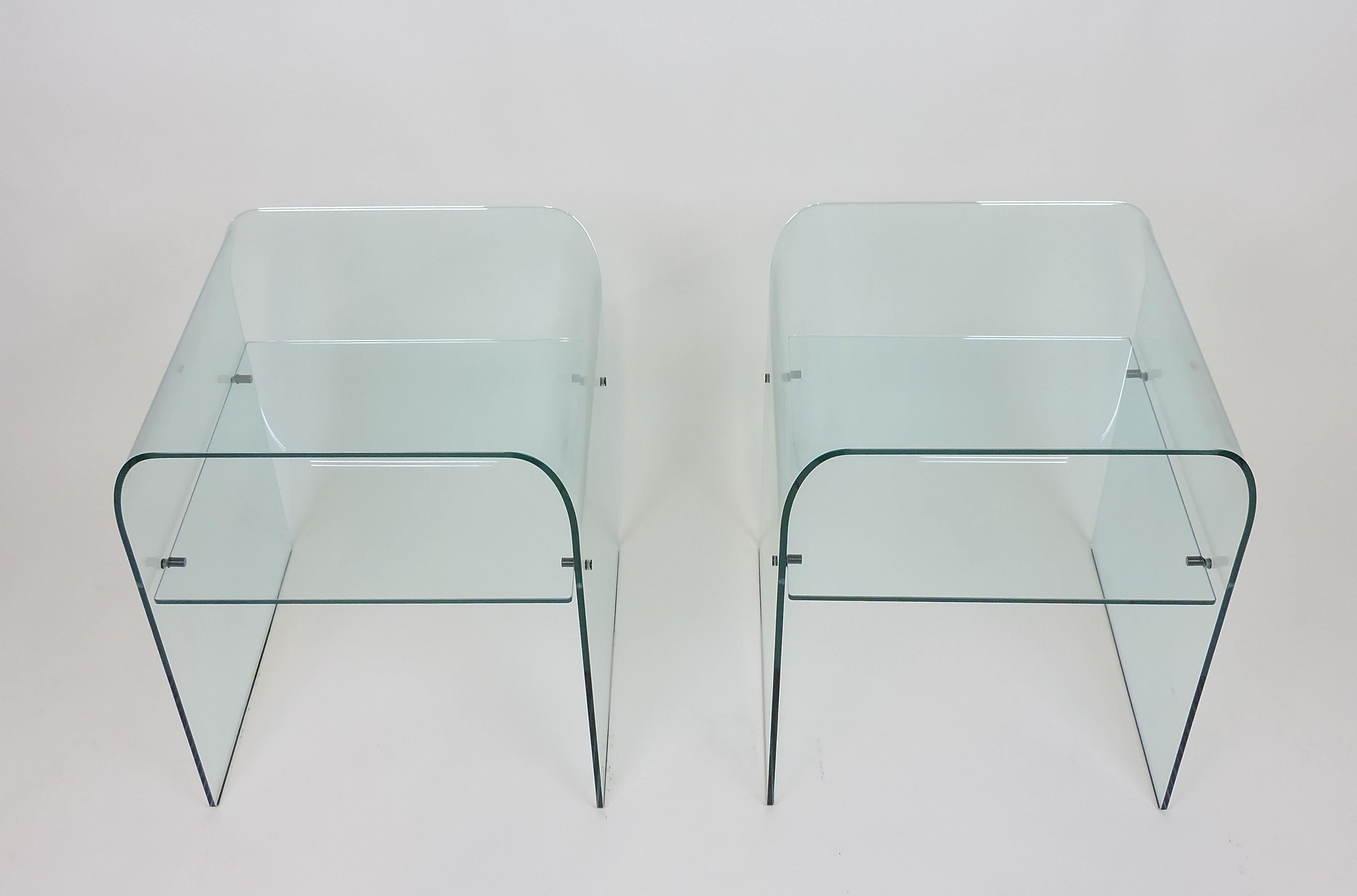 Beautiful set of two end tables or nightstands manufactured in Italy by Fiam Italia. These high quality tables are made of clear curved glass and are perfect for when you don't want a lot of visual weight. Both have removable glass shelves, plastic