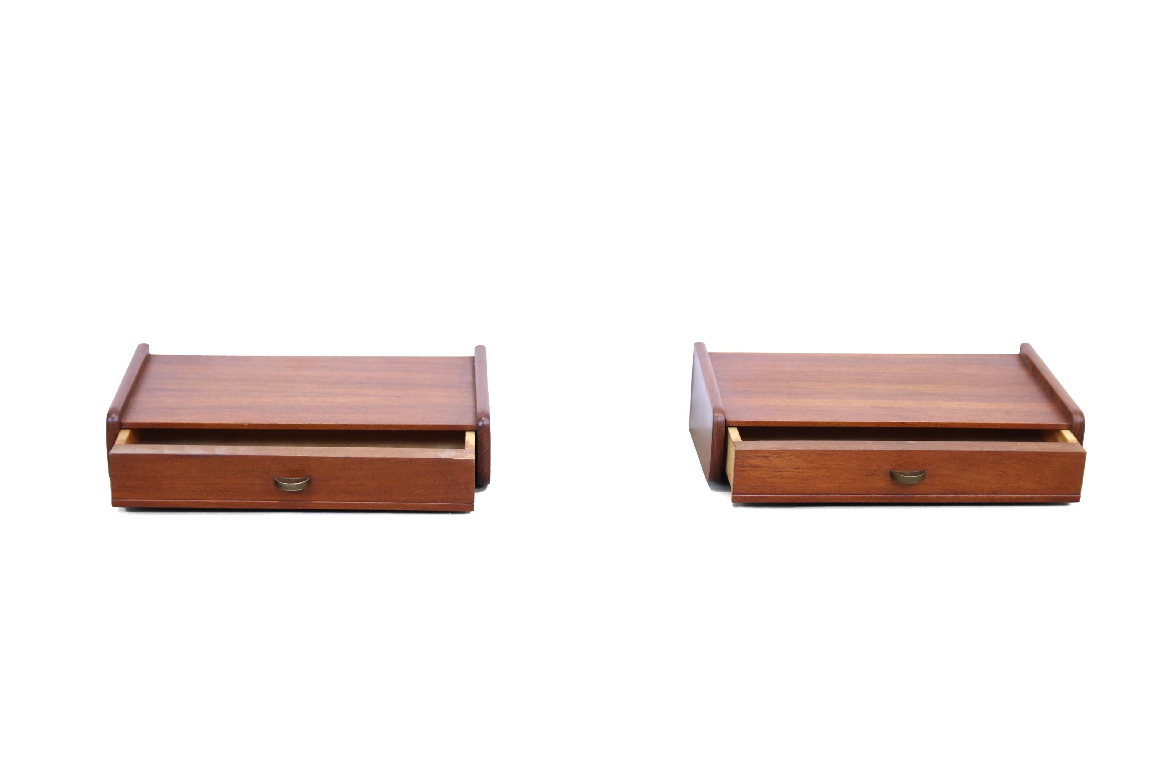 Very beautiful and minimalistic floating bedside table from Denmark made of teak. The cabinets are blindly attached to the wall and both have one drawer with a brass handle. Due to the simple design, this cabinet fits well in any bedroom.