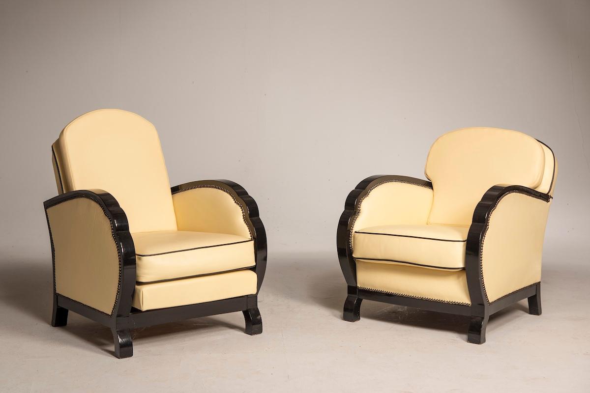 The entire ensemble features elegant black leather details contrasted by ivory-colored leather cushions. One of the armchairs is reclining, while the second has a fixed backrest, as does the sofa. The cushions have been newly made, while the wooden
