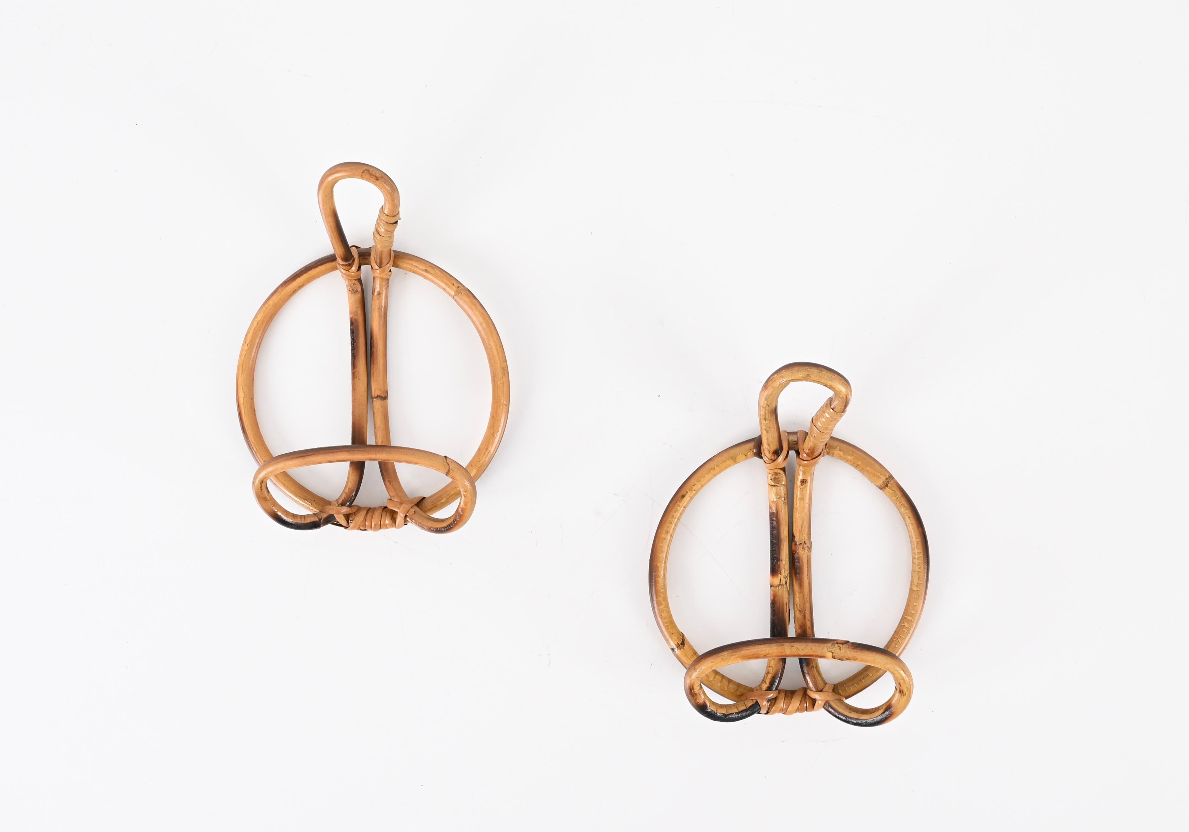 Beautiful set of two French Riviera round coat hangers in curved rattan and wicker. These stylish coat hooks were designed in Italy during the 1960s following the French Riviera trend.

These gorgeous items feature a sturdy round frame that holds a