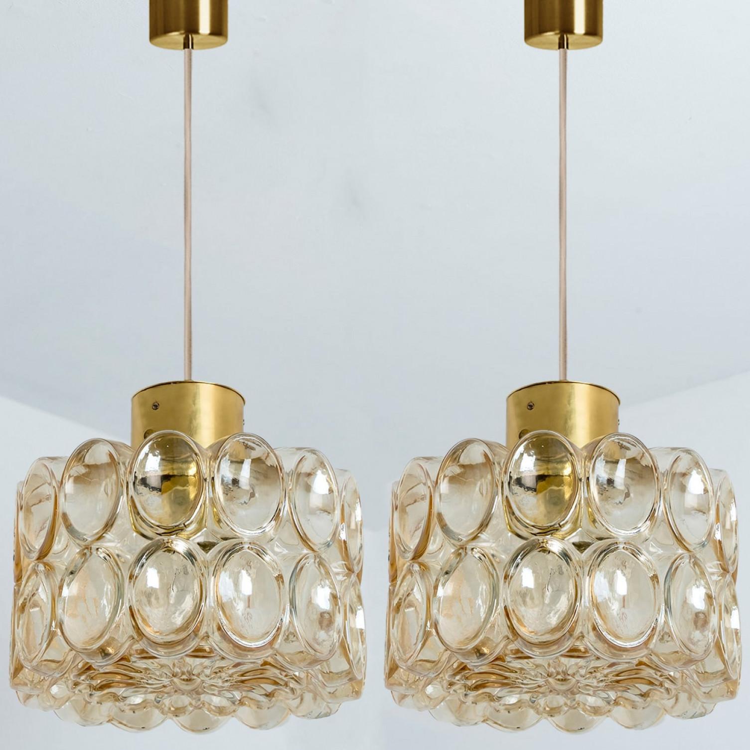 Coppia di bellissime lampade a sospensione in vetro a bolle disegnate da Helena Tynell per Glashütte Limburg, 1960. Un design di classe, il vetro soffiato a mano di colore ambrato/tonico dona una meravigliosa luce calda.

Helena Tynell è una