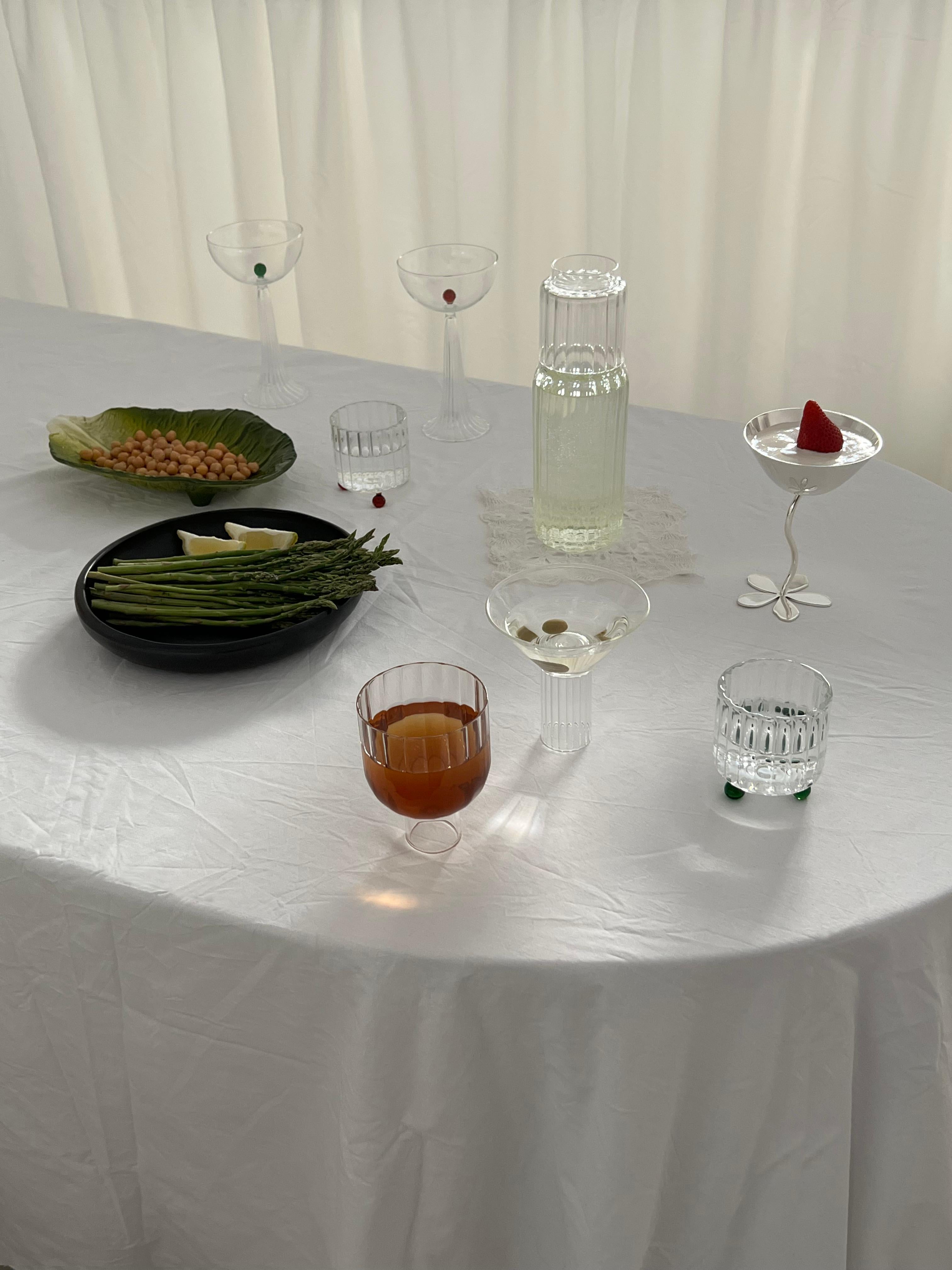 Un verre lowball de forme atypique, inspiré de l'architecture postmoderne. Chaque pièce est fabriquée à la main en Italie par des maîtres verriers qui utilisent du verre borosilicaté de haute qualité. Le corps en verre strié repose sur trois sphères