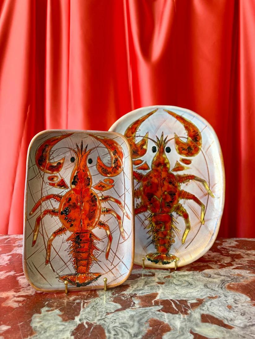 Paire de plats de service en céramique de Monique Brunner, Vallauris, France, datant du milieu du XXe siècle. Cet ensemble comprend un plat ovale et un plat rectangulaire, tous deux peints à la main avec des motifs marins stylisés dans des tons